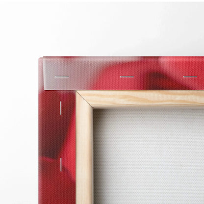 Close-up of a wooden frame corner with vibrant red rose design printed on canvas stretched and stapled for wall art decor.