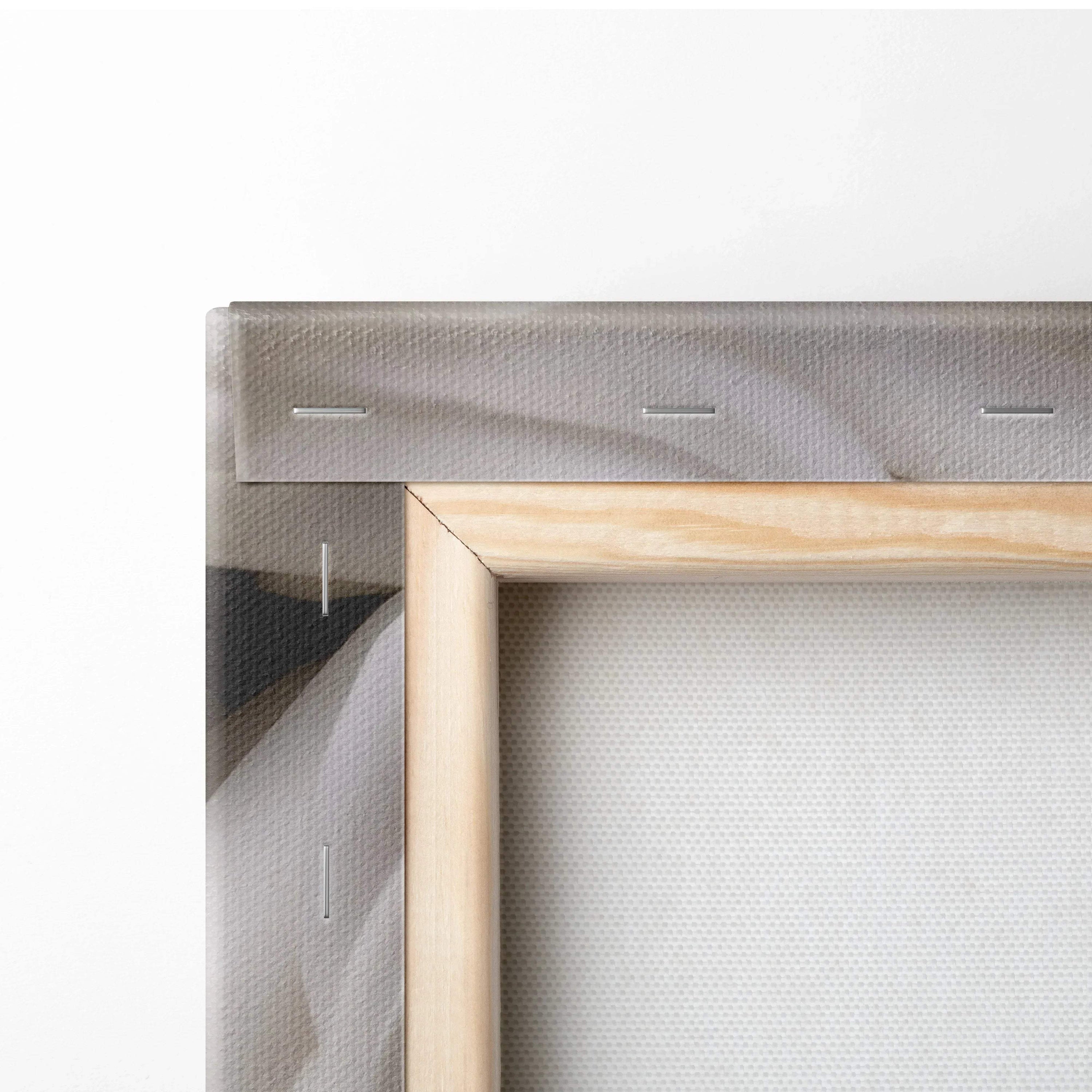 Close-up of wooden frame and back of stretched white canvas wall art with visible staple details.