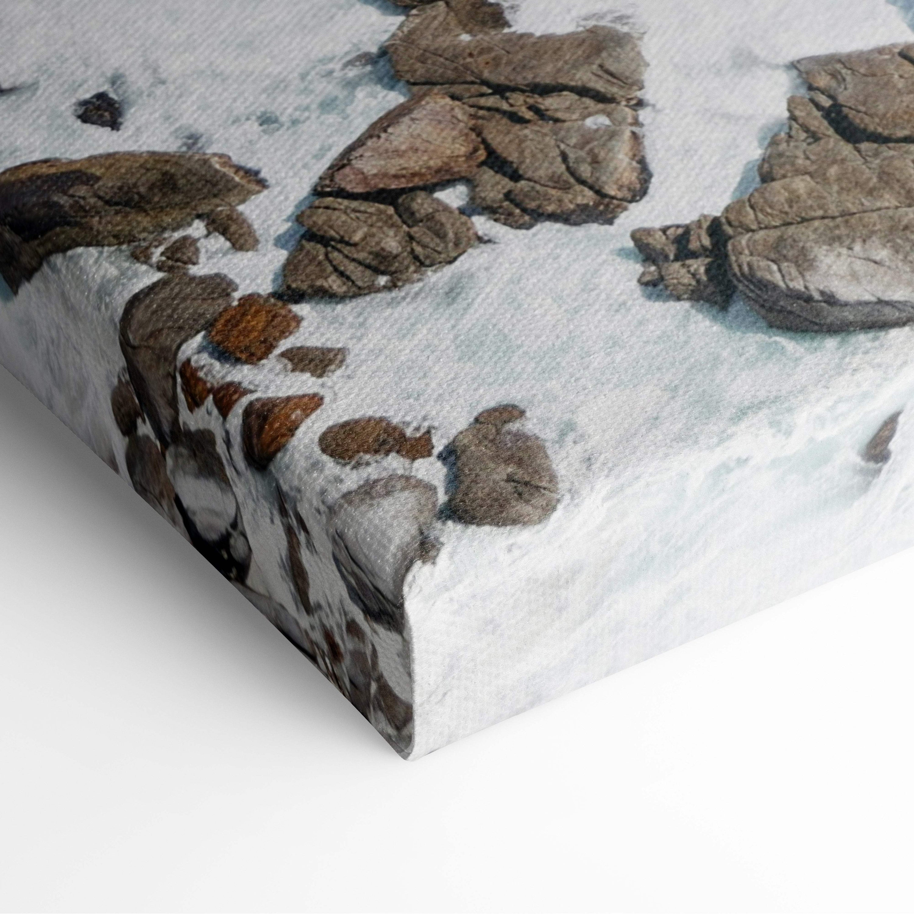 Aerial turquoise ocean canvas wall art print featuring rugged snow-dusted rocks in earthy brown and gray tones