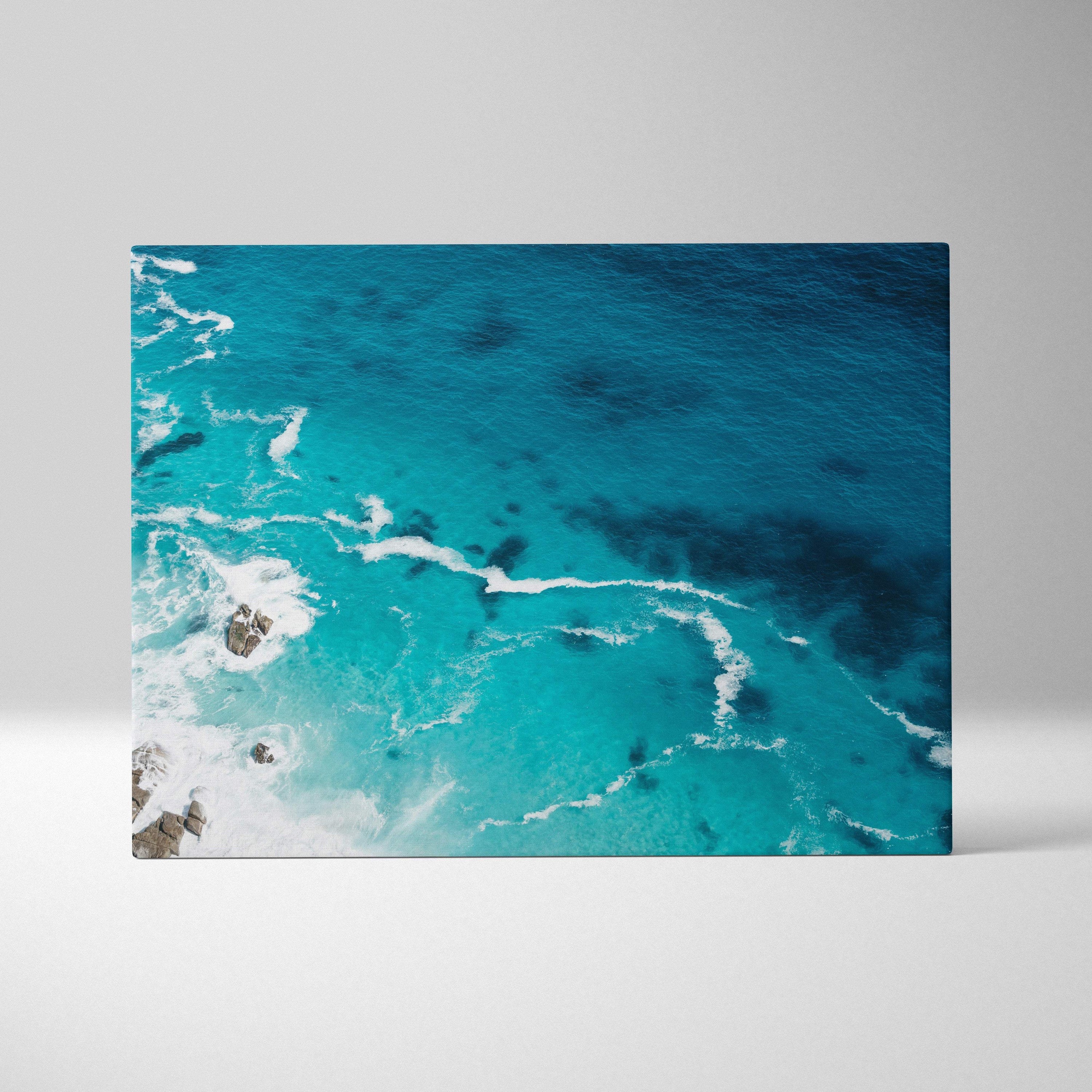 Rectangular canvas print of a vibrant turquoise ocean with white foamy waves crashing on dark rocks for coastal decor