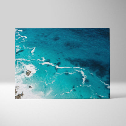 Rectangular canvas print of a vibrant turquoise ocean with white foamy waves crashing on dark rocks for coastal decor