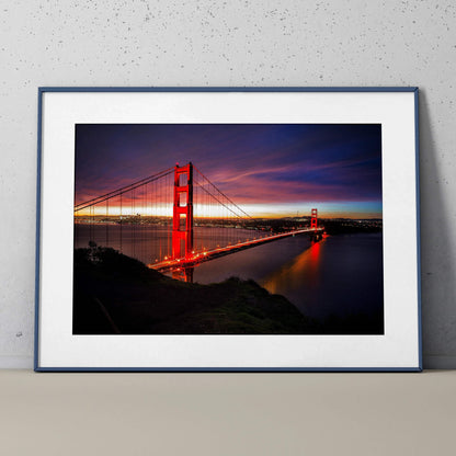 Golden Gate Bridge at night with vibrant city lights wall art poster in a black frame.