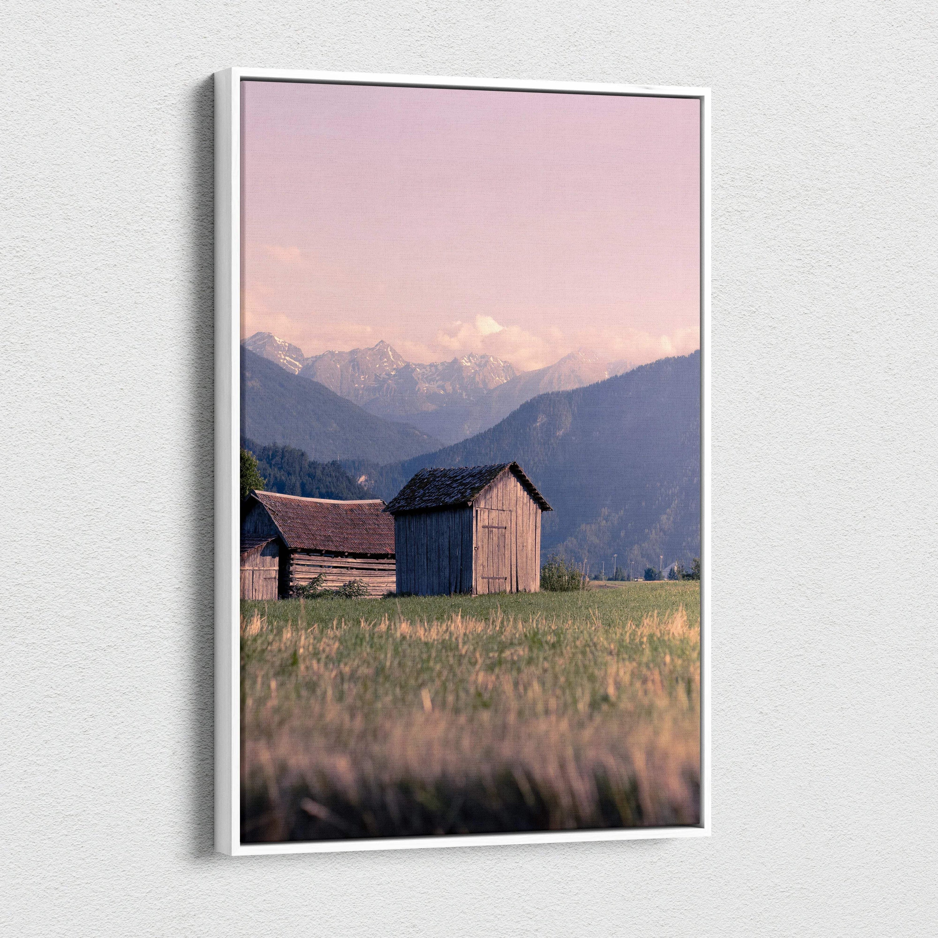 Canvas wall art featuring wooden buildings with mountains and a pink sunset sky.