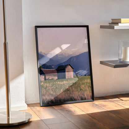 Majestic mountain nature wall art poster with rustic cabin and grassy field in soft light.
