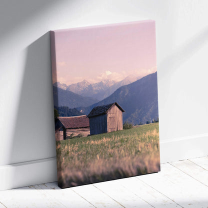 Canvas wall art featuring golden sunset over mountains with rustic wooden buildings in the foreground.
