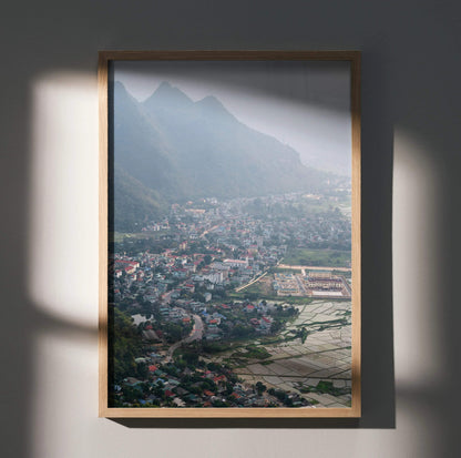 Vertical urban cityscape poster with misty mountains and town, framed wall art print.
