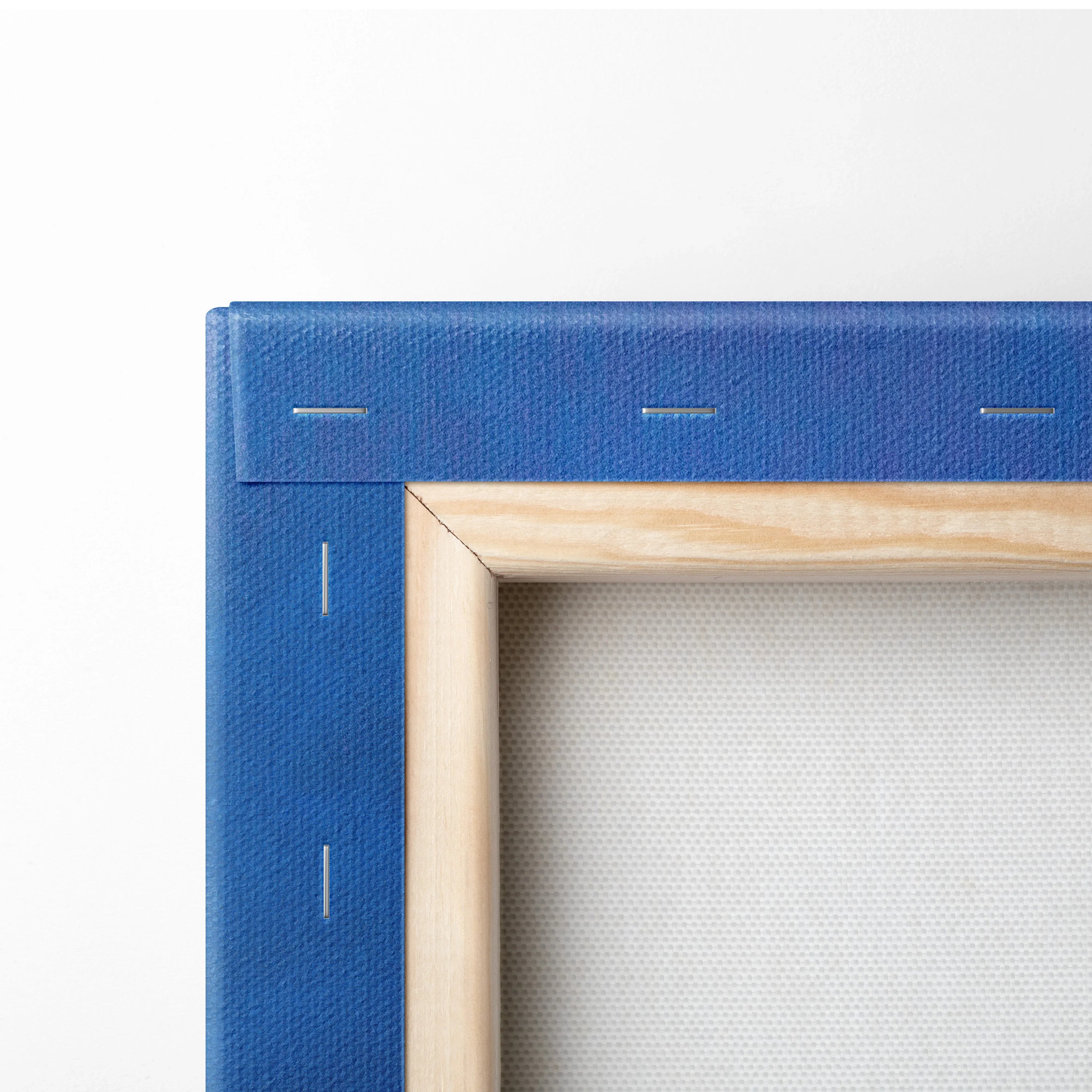 Blue canvas wrapped around wooden frame corner showing stapled edges for wall art decor.