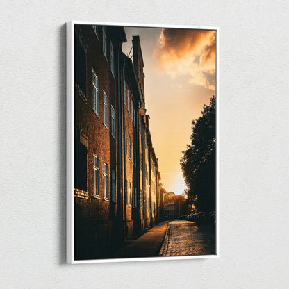 Vertical canvas wall art featuring a city skyline at sunset with golden light on brick buildings.