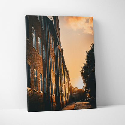Canvas wall art featuring a sunset city skyline with warm light on brick buildings and shadows.
