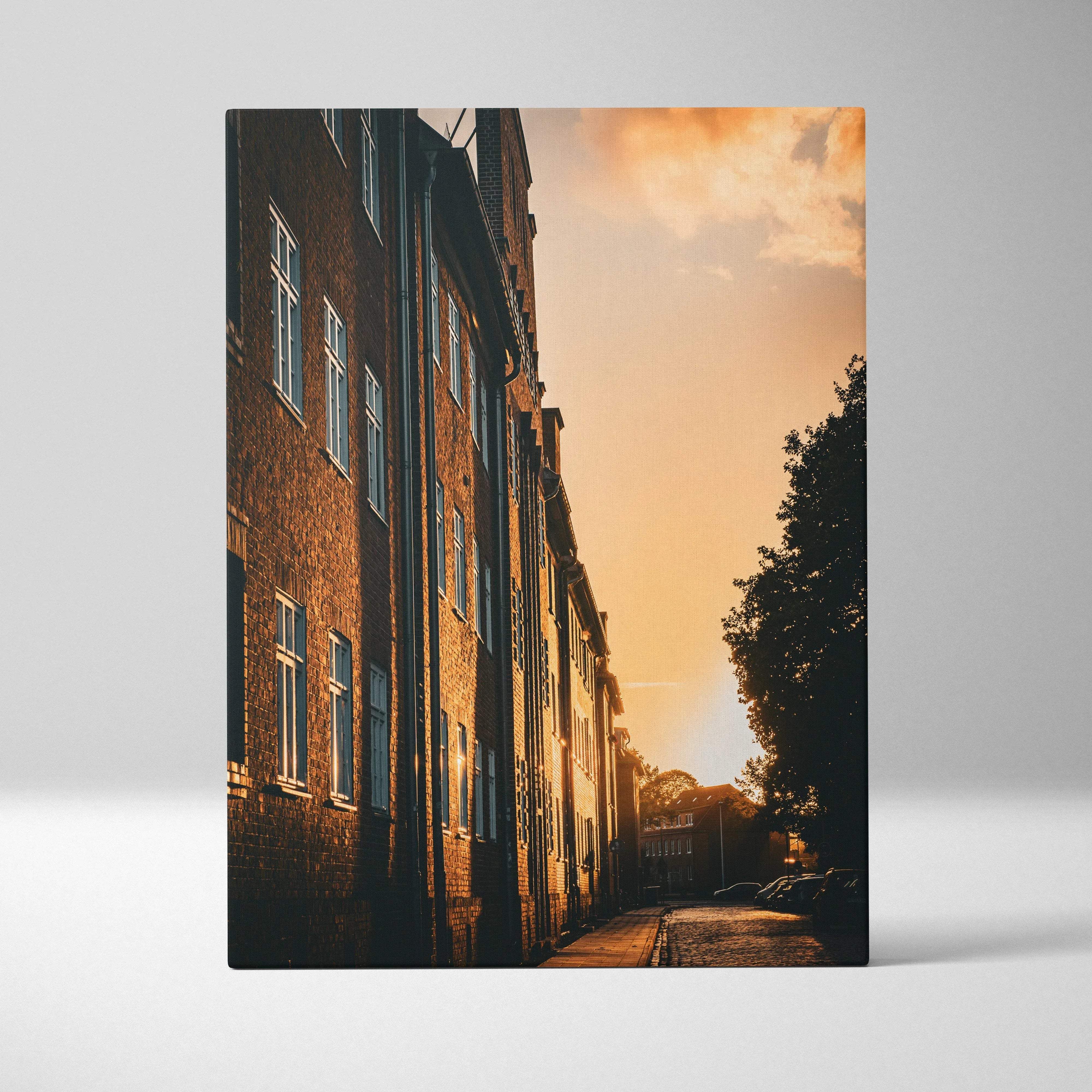 A rectangular canvas print of a warm-toned urban street scene with brick buildings at golden hour light