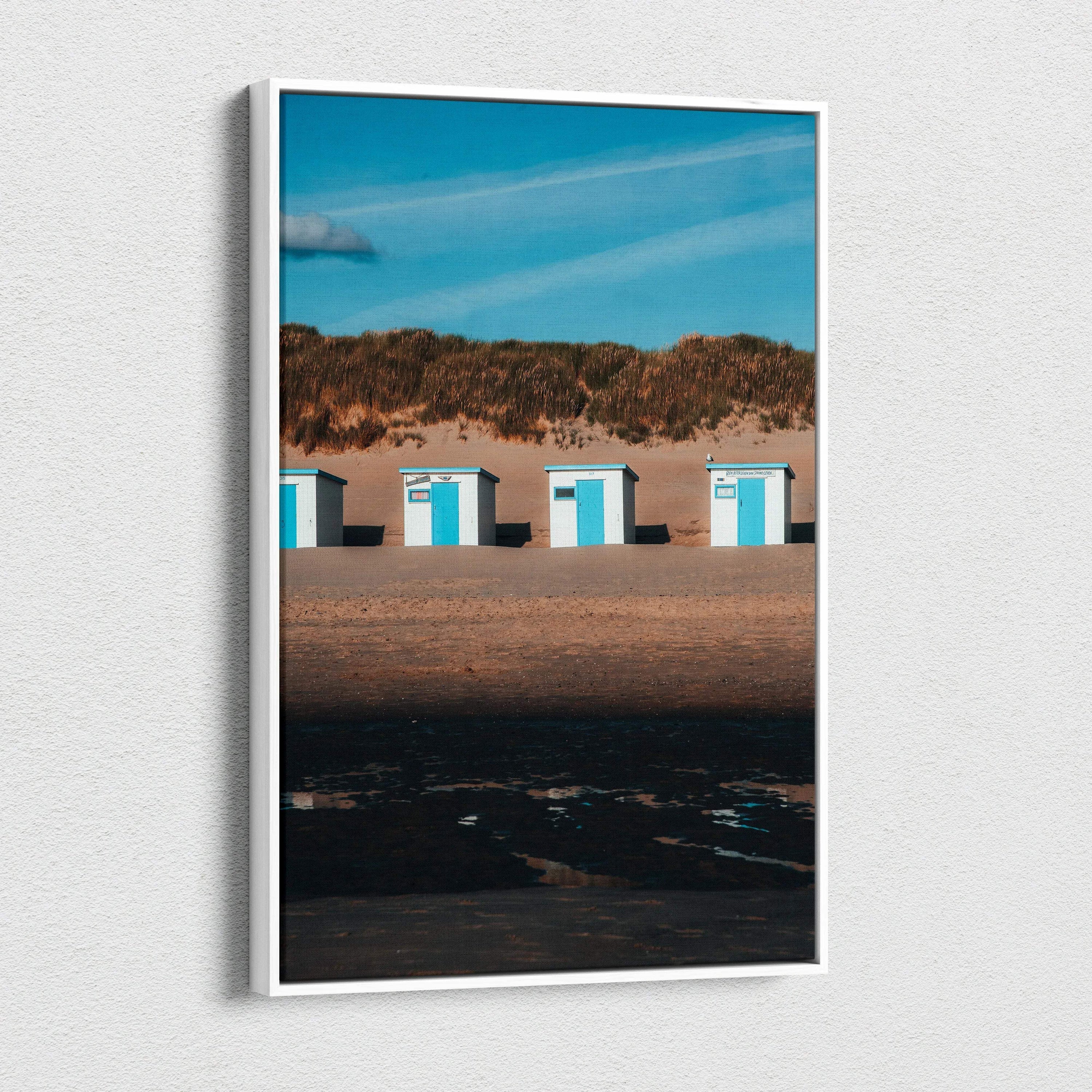 Vertical beach scene canvas wall art with white beach huts and blue sky.