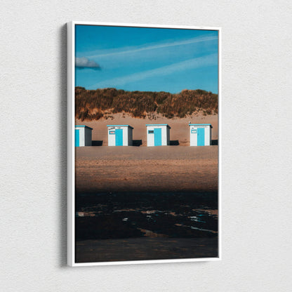 Vertical beach scene canvas wall art with white beach huts and blue sky.