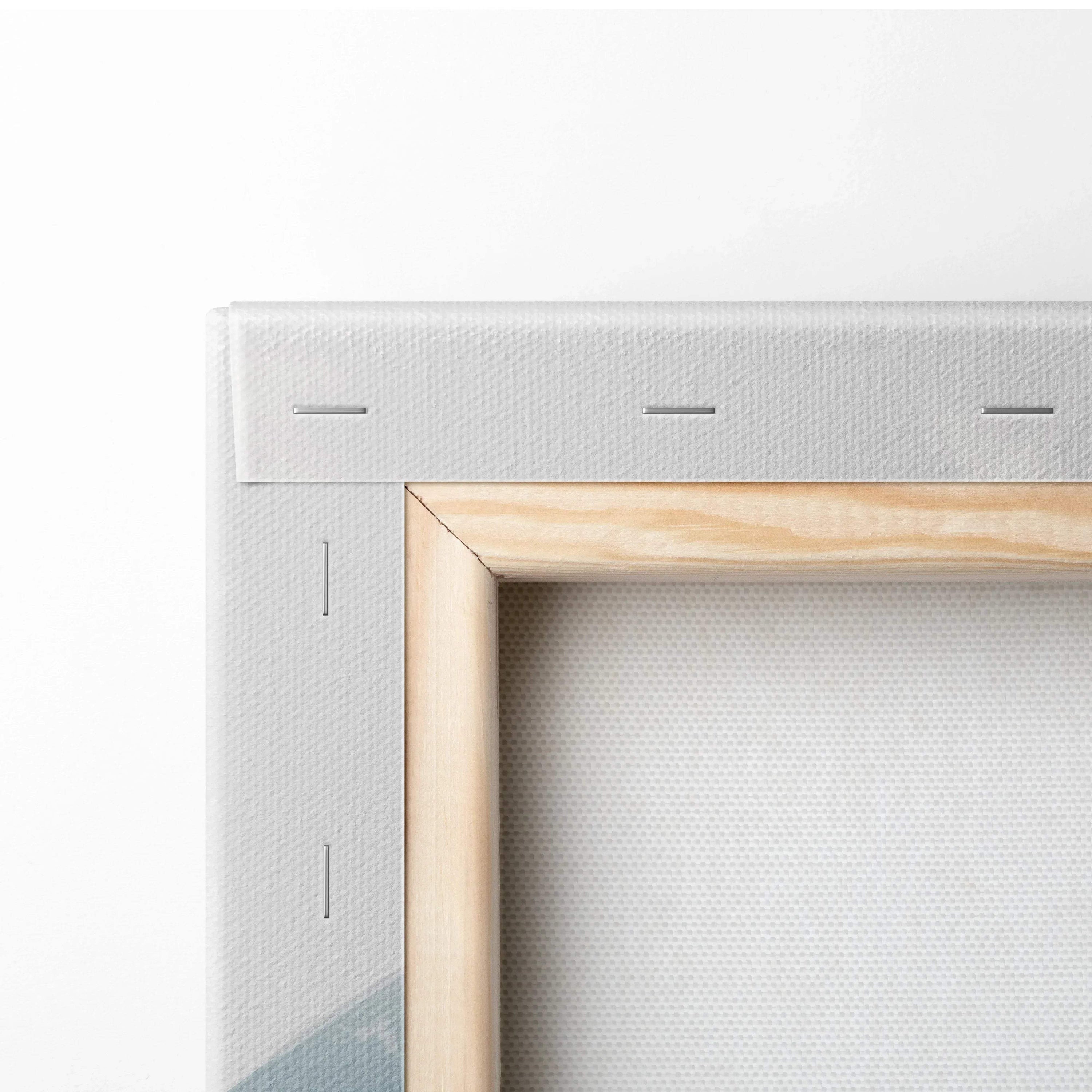 Close-up of wooden frame corner on white canvas wall art with visible stapled edges.