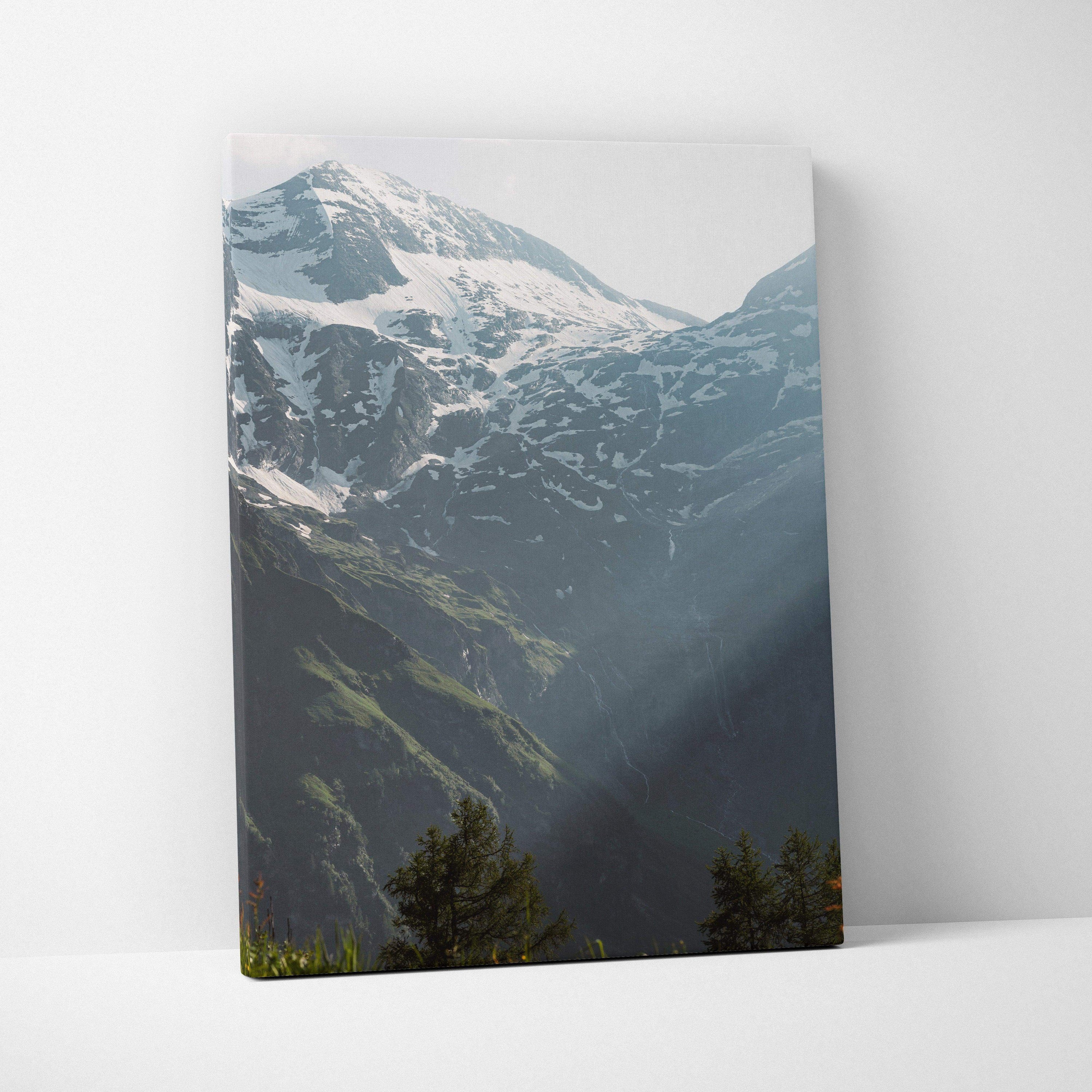 Vertical canvas wall art featuring snow-capped mountain peaks with sunlight and pine trees in foreground.
