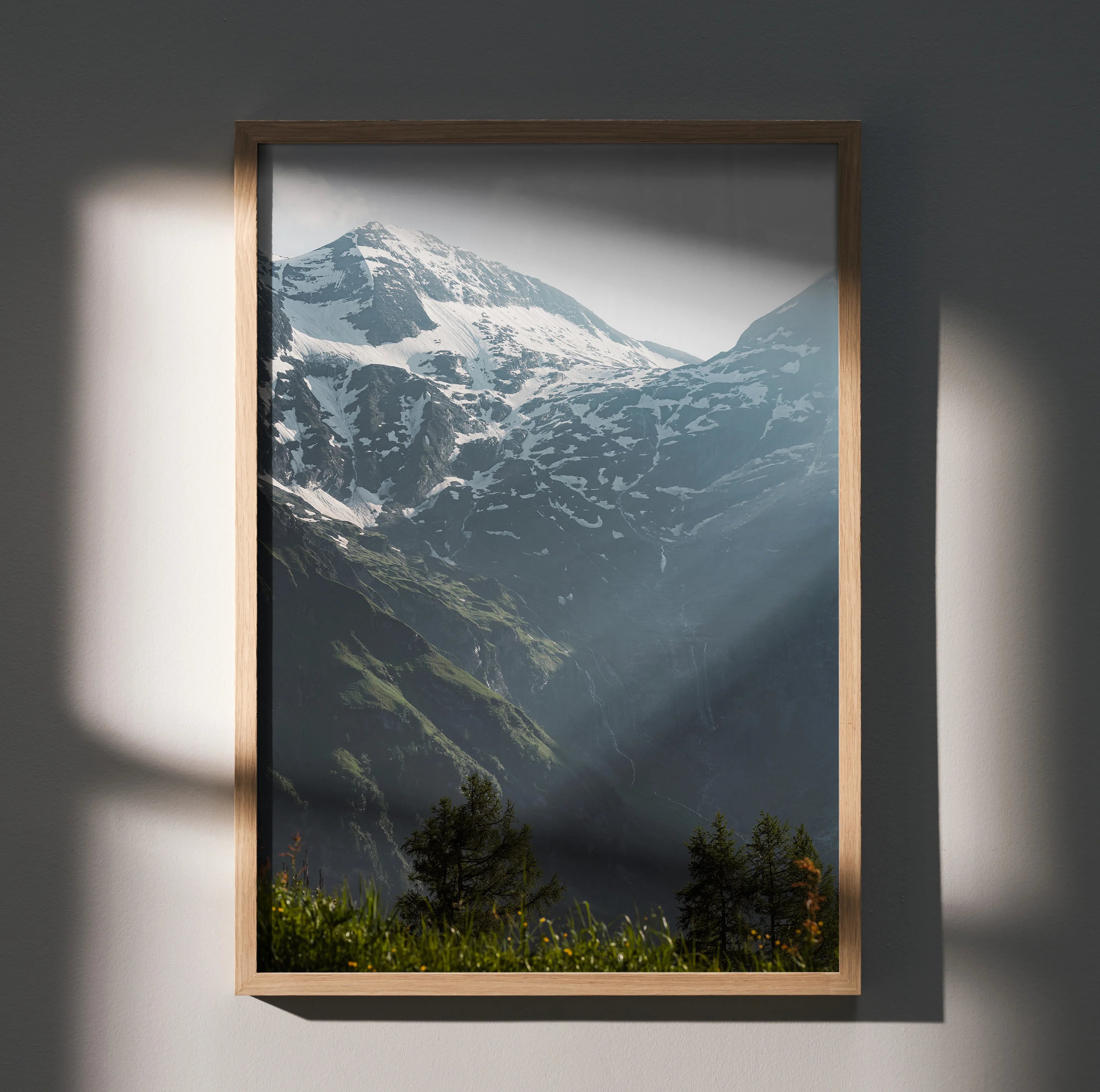 Vertical wall art poster featuring snow-capped mountains with sunlight and green forest foreground.