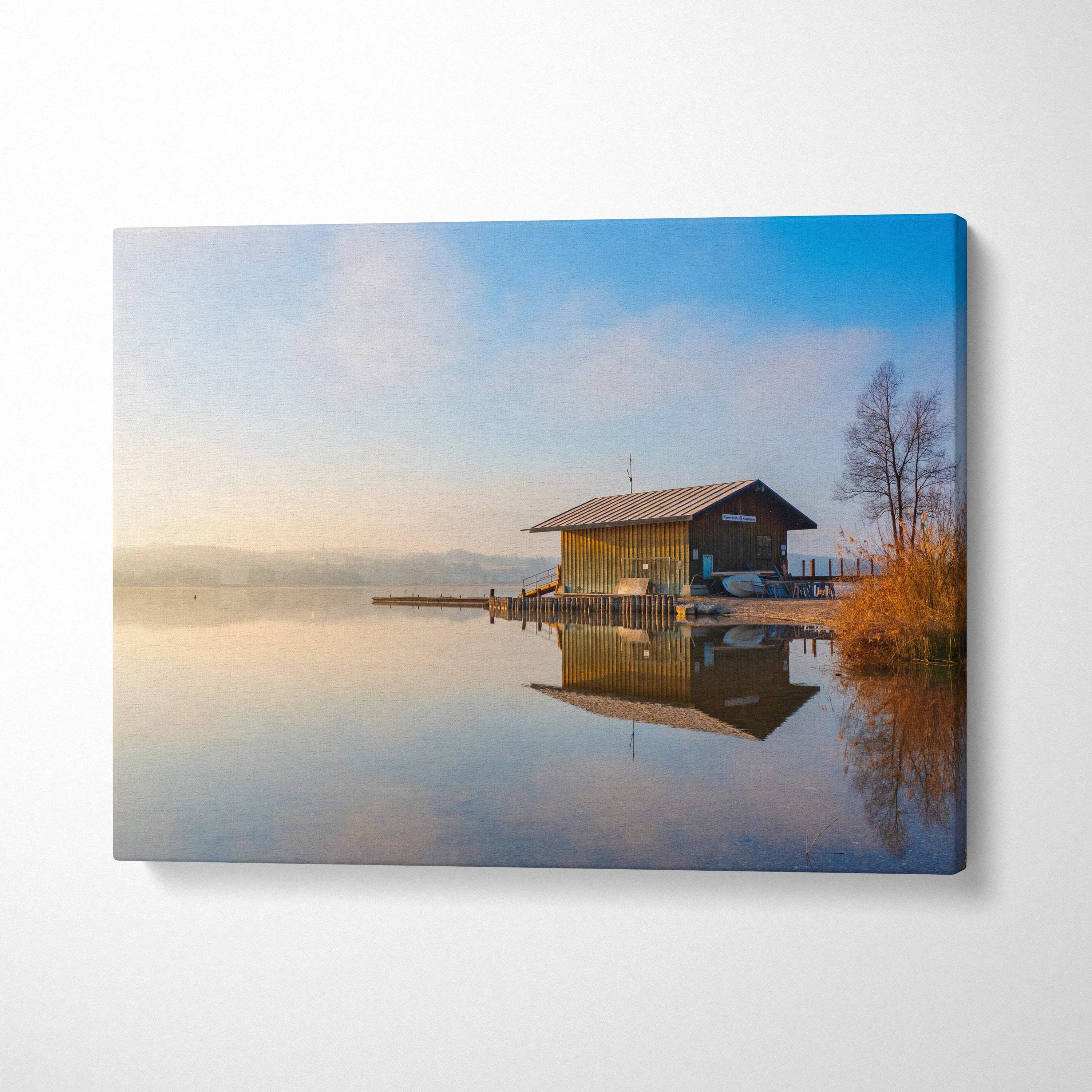 Canvas wall art showing tranquil lakeside building reflected in calm water under soft morning sky.