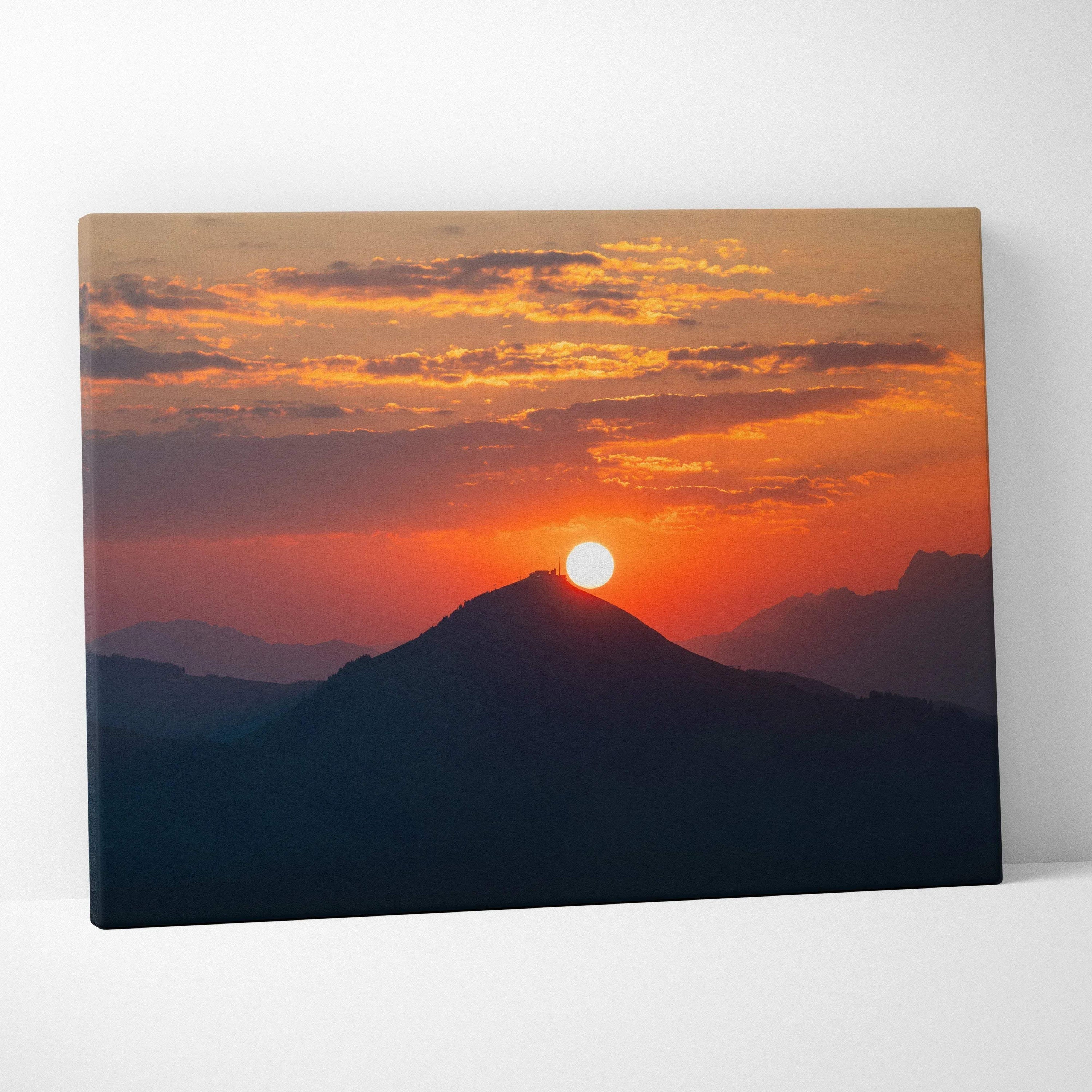 Canvas wall art of a vivid sunset over silhouetted mountain peaks with warm orange and red sky tones.
