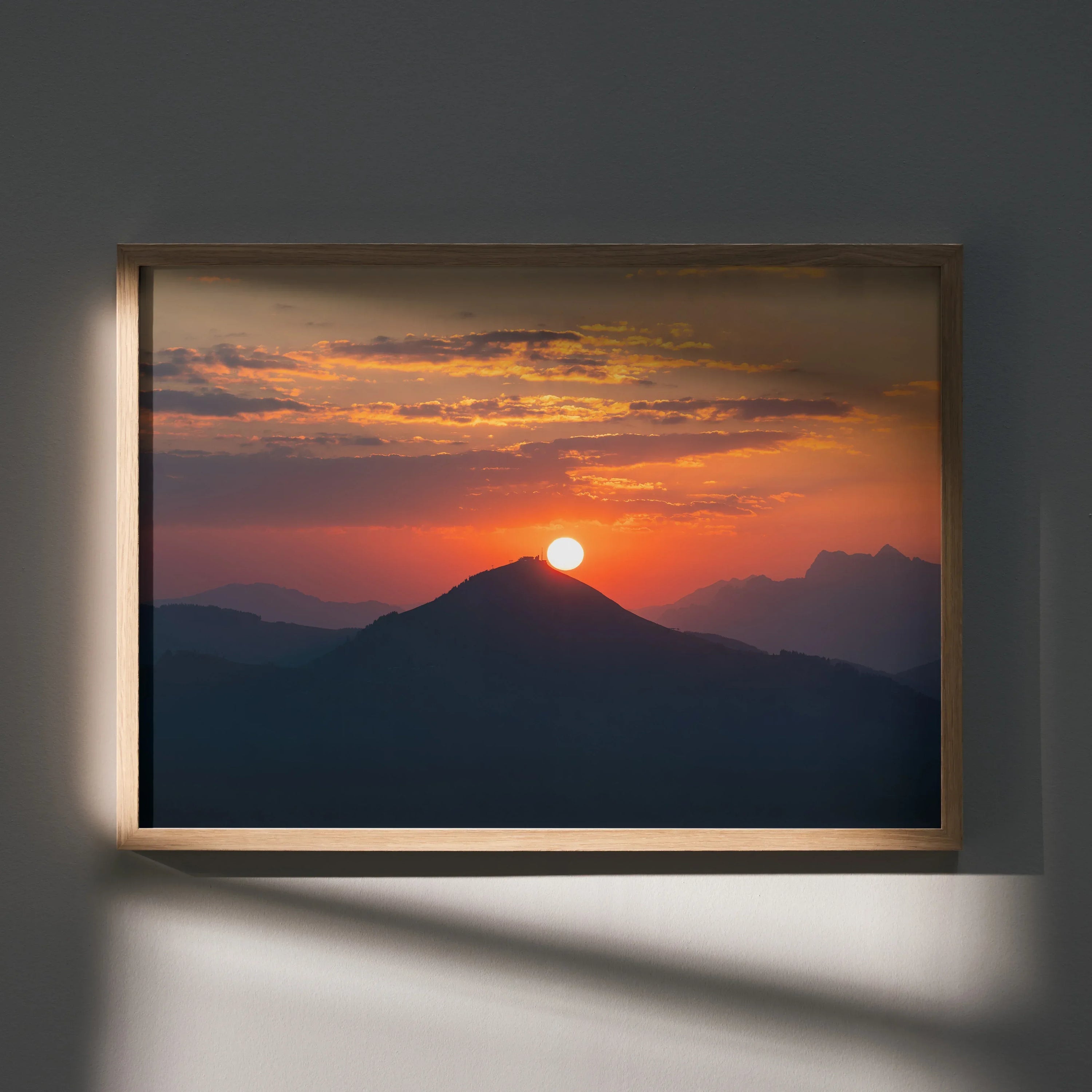 Sunset over mountain silhouette with vibrant orange sky framed as wall art poster.