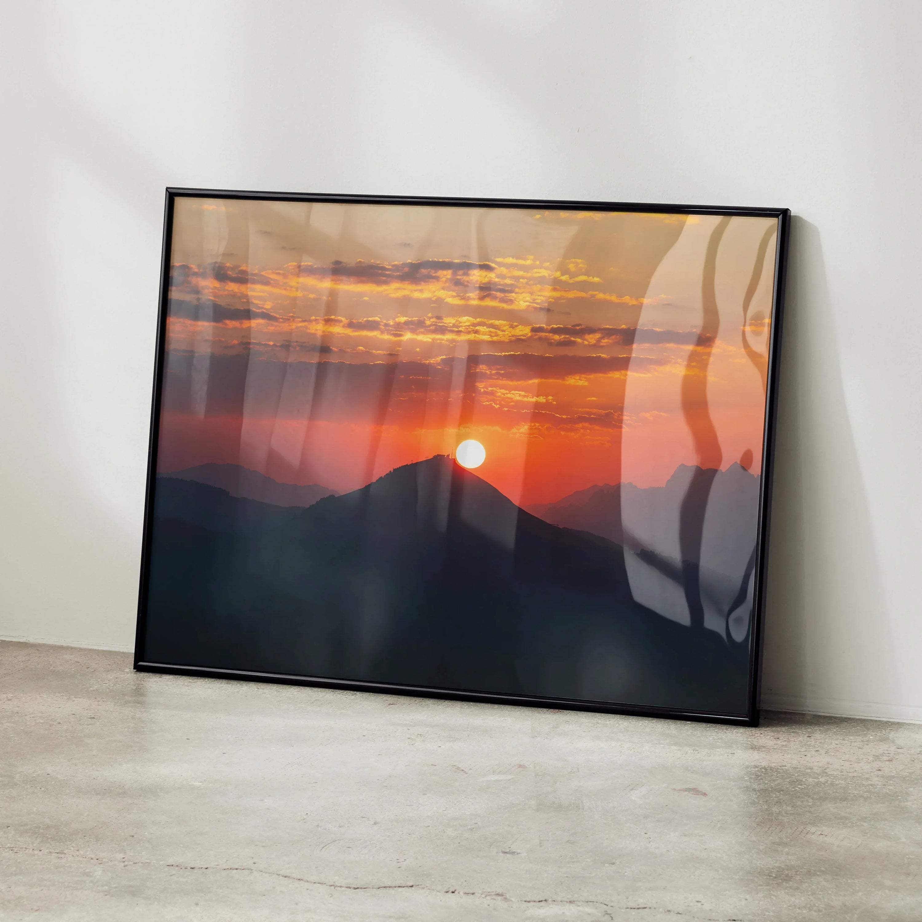 Vibrant mountains sunset wall art poster with orange and red sky in black frame.
