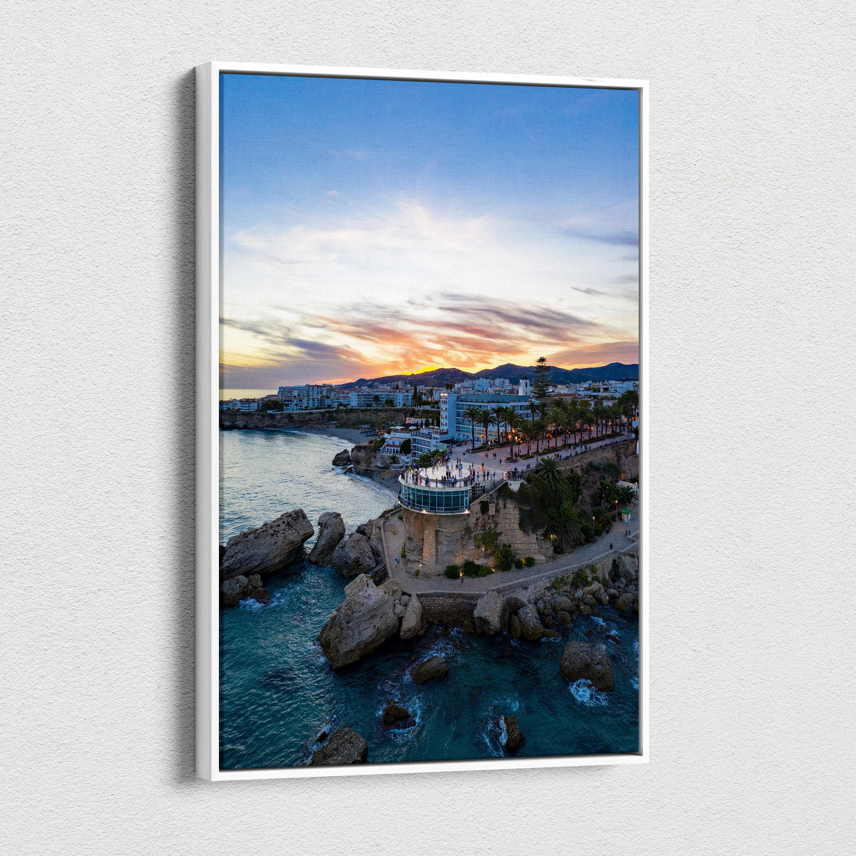 Canvas wall art featuring vibrant city skyline at sunset over rocky coastline and water.