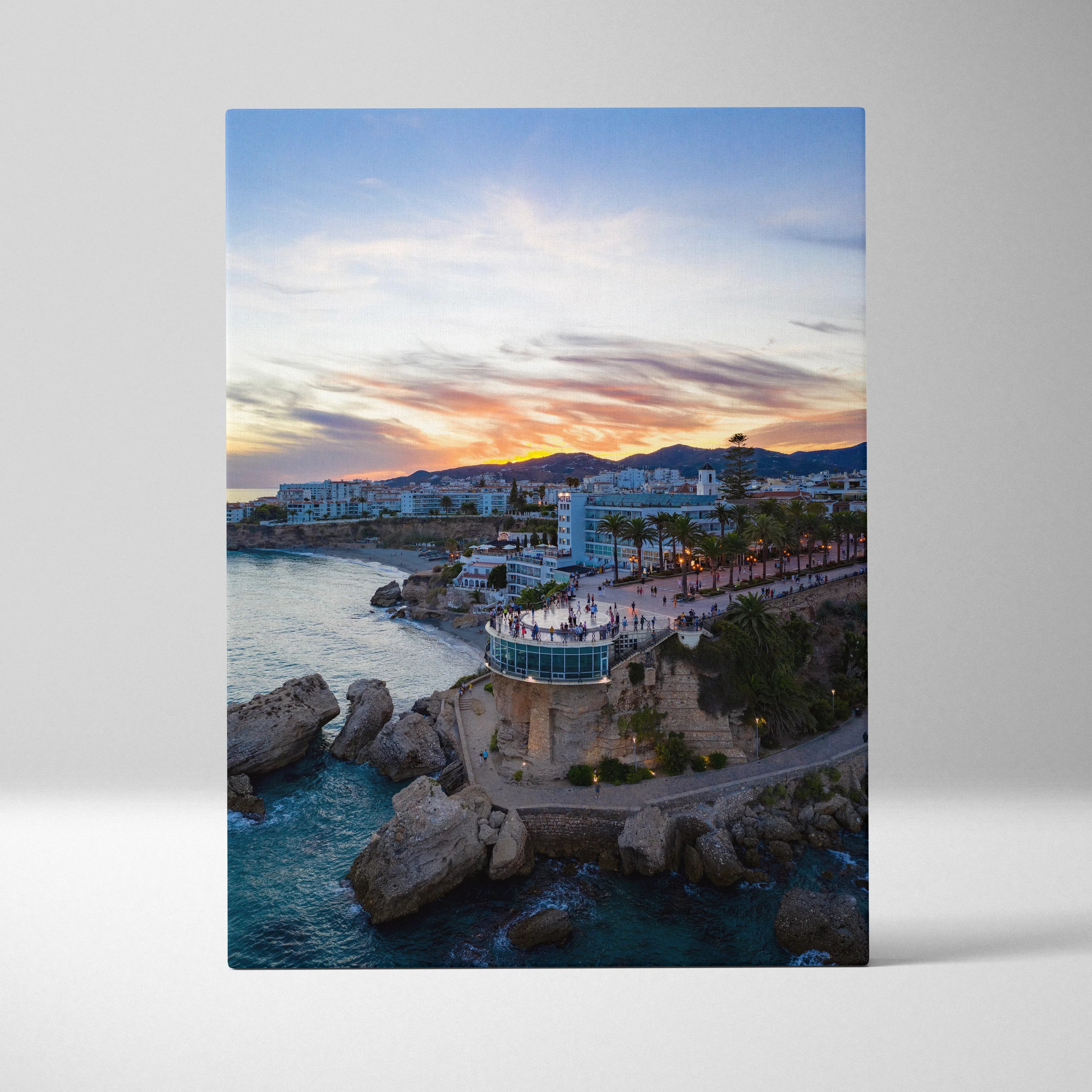 Vertical canvas wall art featuring a city skyline at sunset with vibrant orange and blue hues over coastal buildings and.