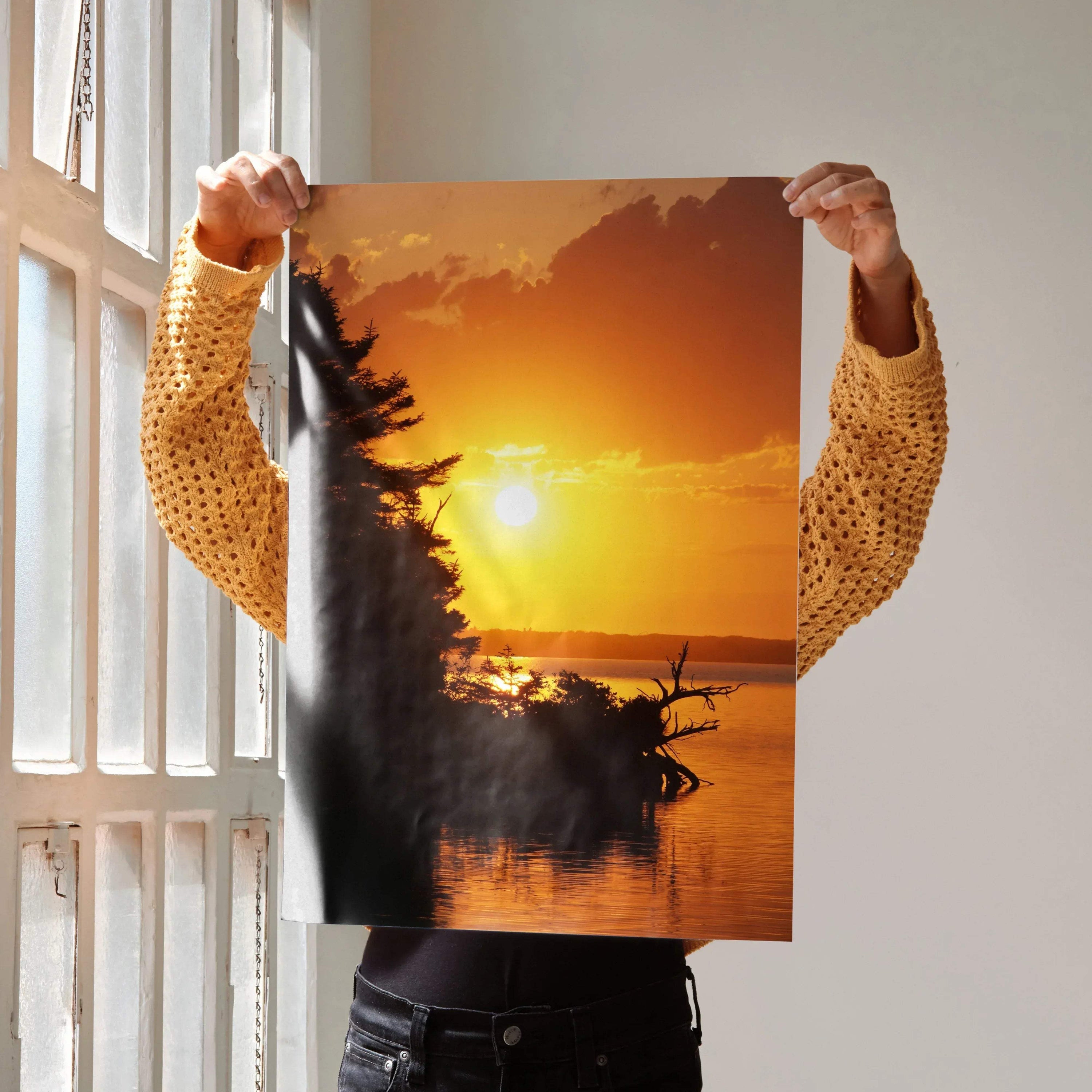 Sunset poster with vibrant orange sky and silhouetted trees over calm water, vertical wall art.
