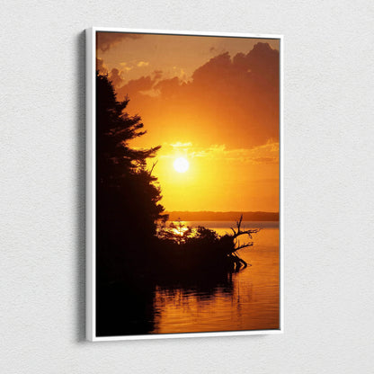 Vertical canvas wall art featuring a vibrant orange beach sunset with silhouetted trees and calm water.