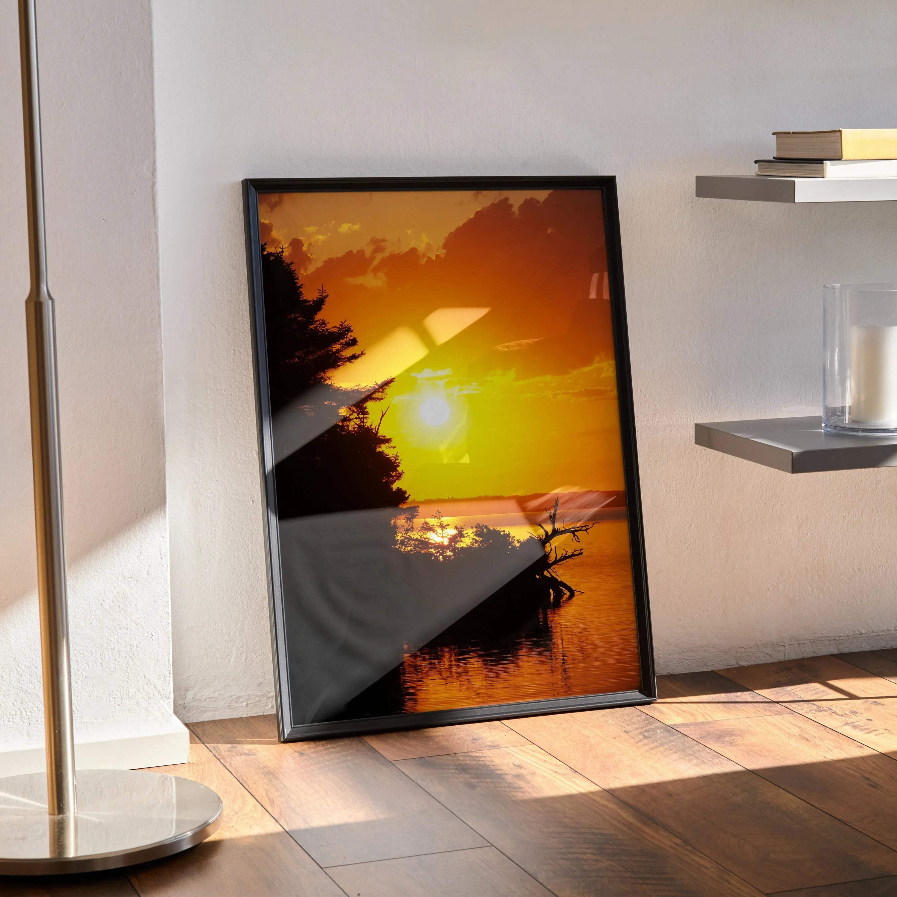 Vertical sunset poster with vibrant orange and yellow sky over calm water, black frame wall art.