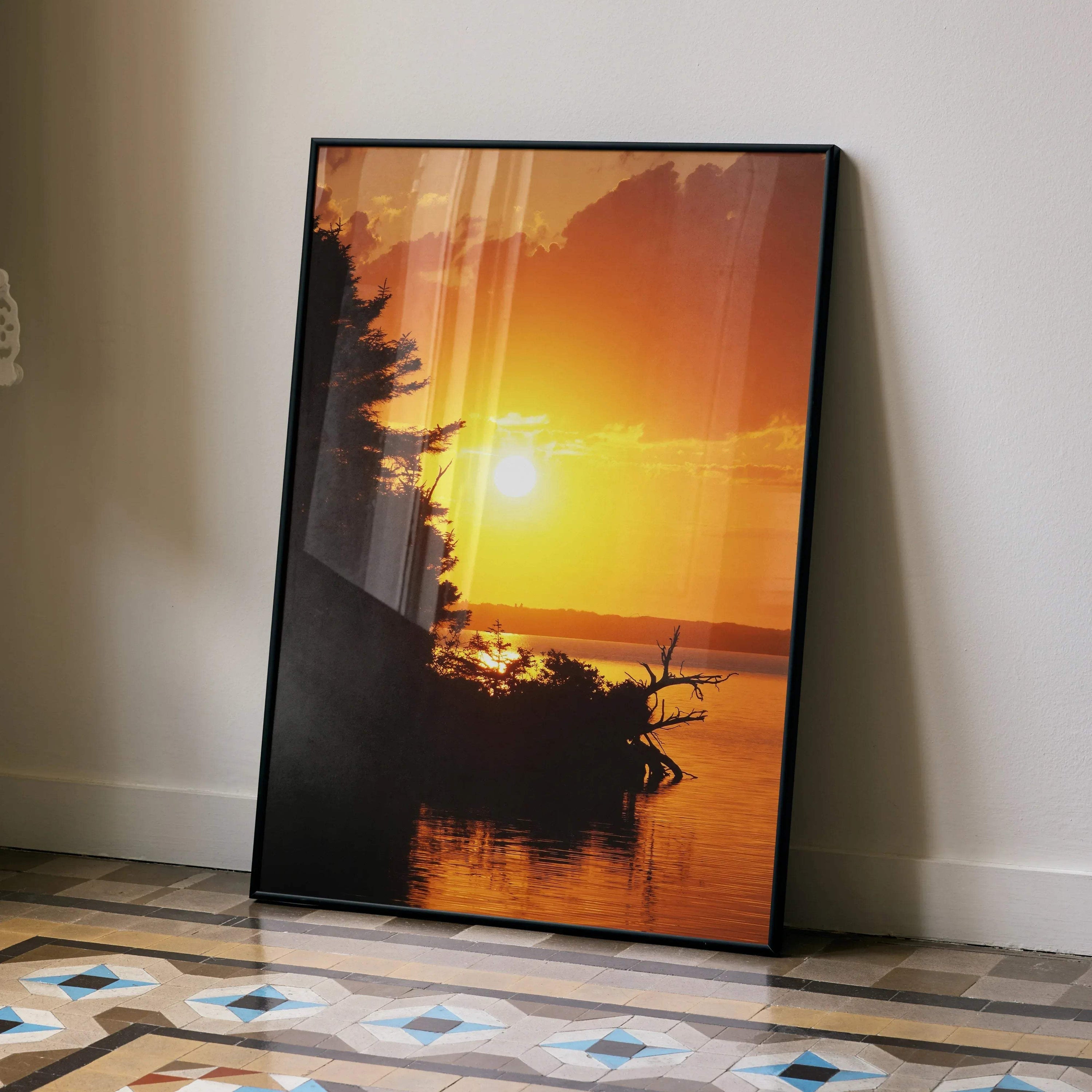 Sunset poster with vibrant orange and yellow sky, silhouetted trees, and calm water wall art in vertical frame.