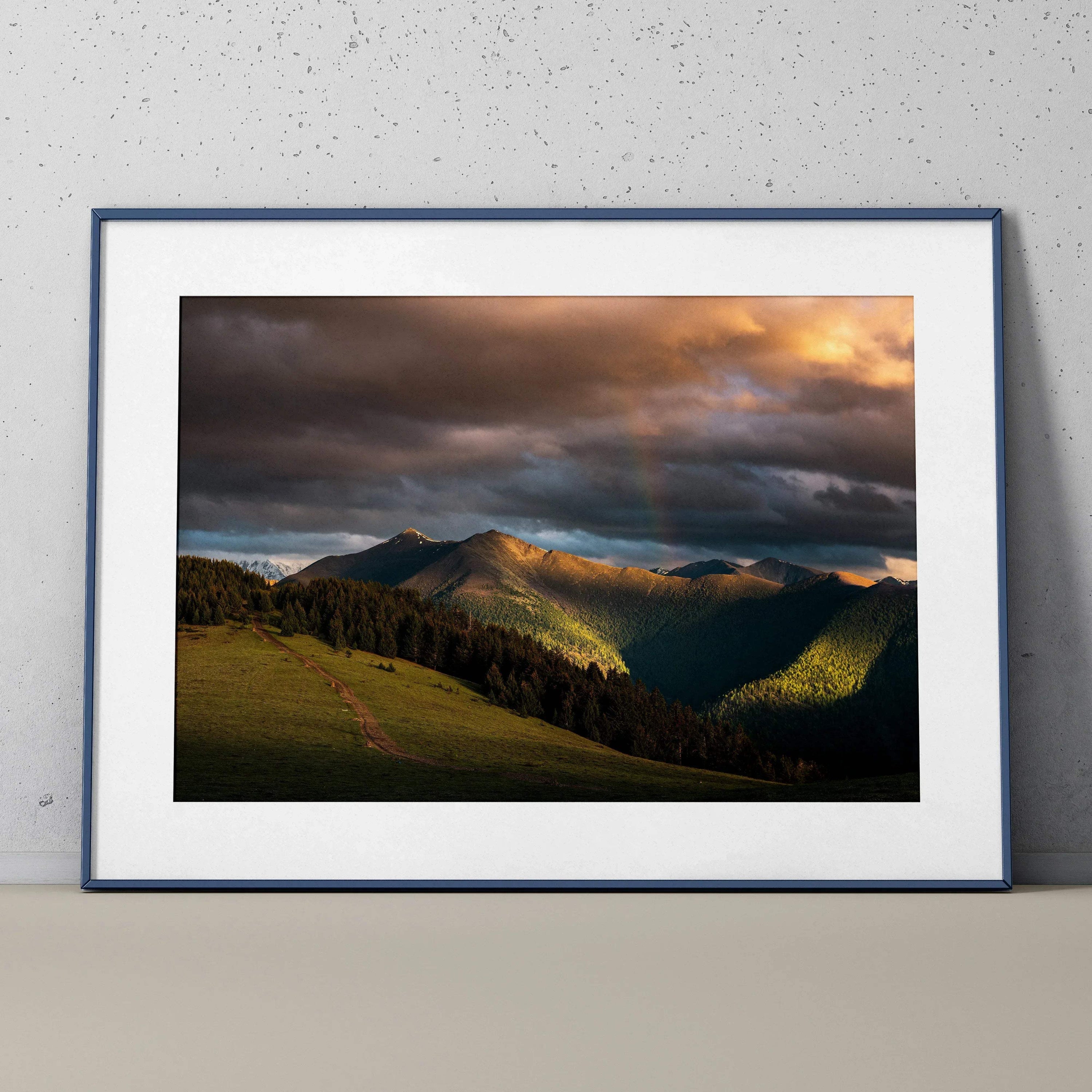 Majestic mountains sunset wall art poster with dramatic clouds and glowing light in black frame.