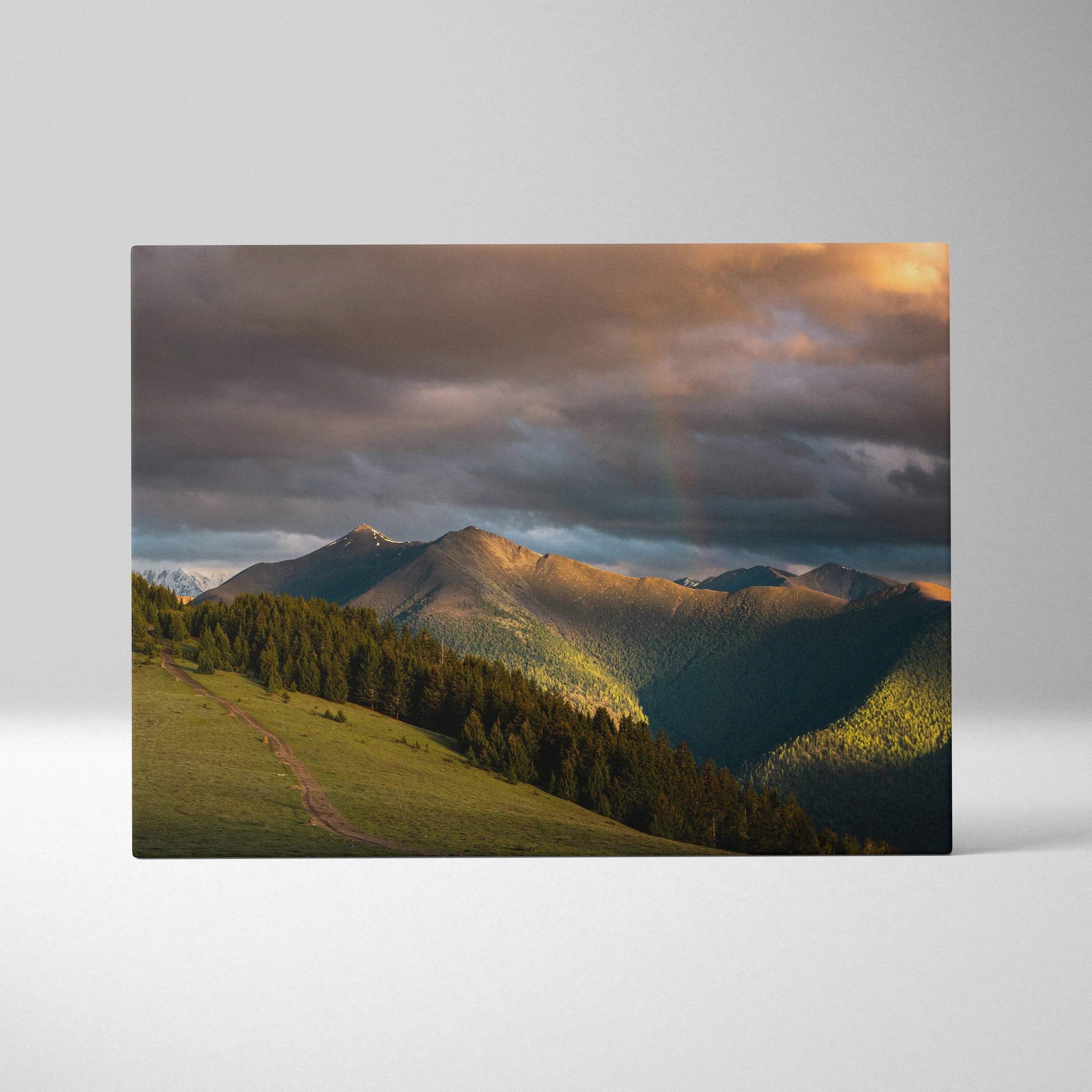 Mountain sunset canvas wall art with golden light and dramatic clouds over forested peaks.
