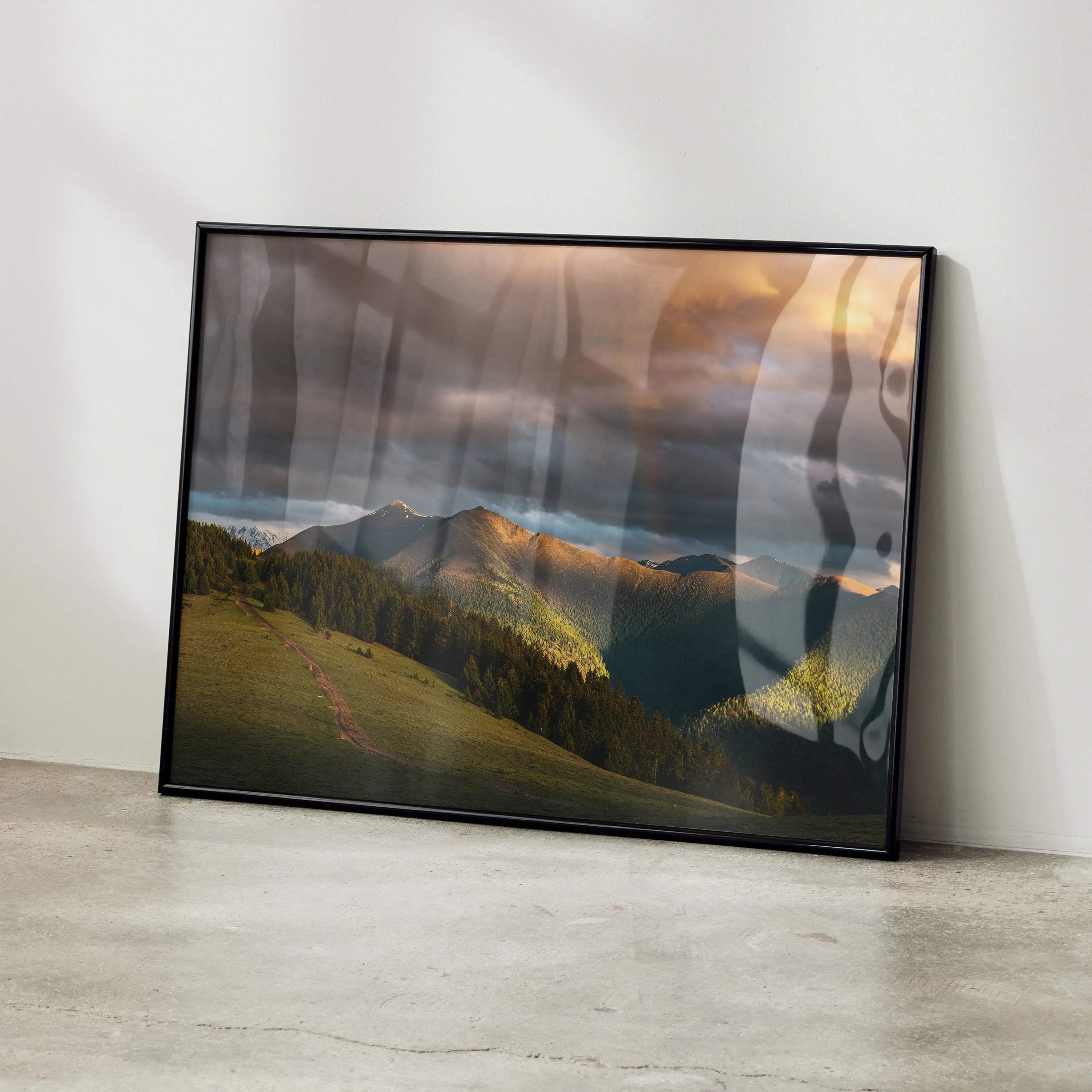 Majestic Mountains Sunset wall art poster with glowing orange sky and lush green hills in a black frame.