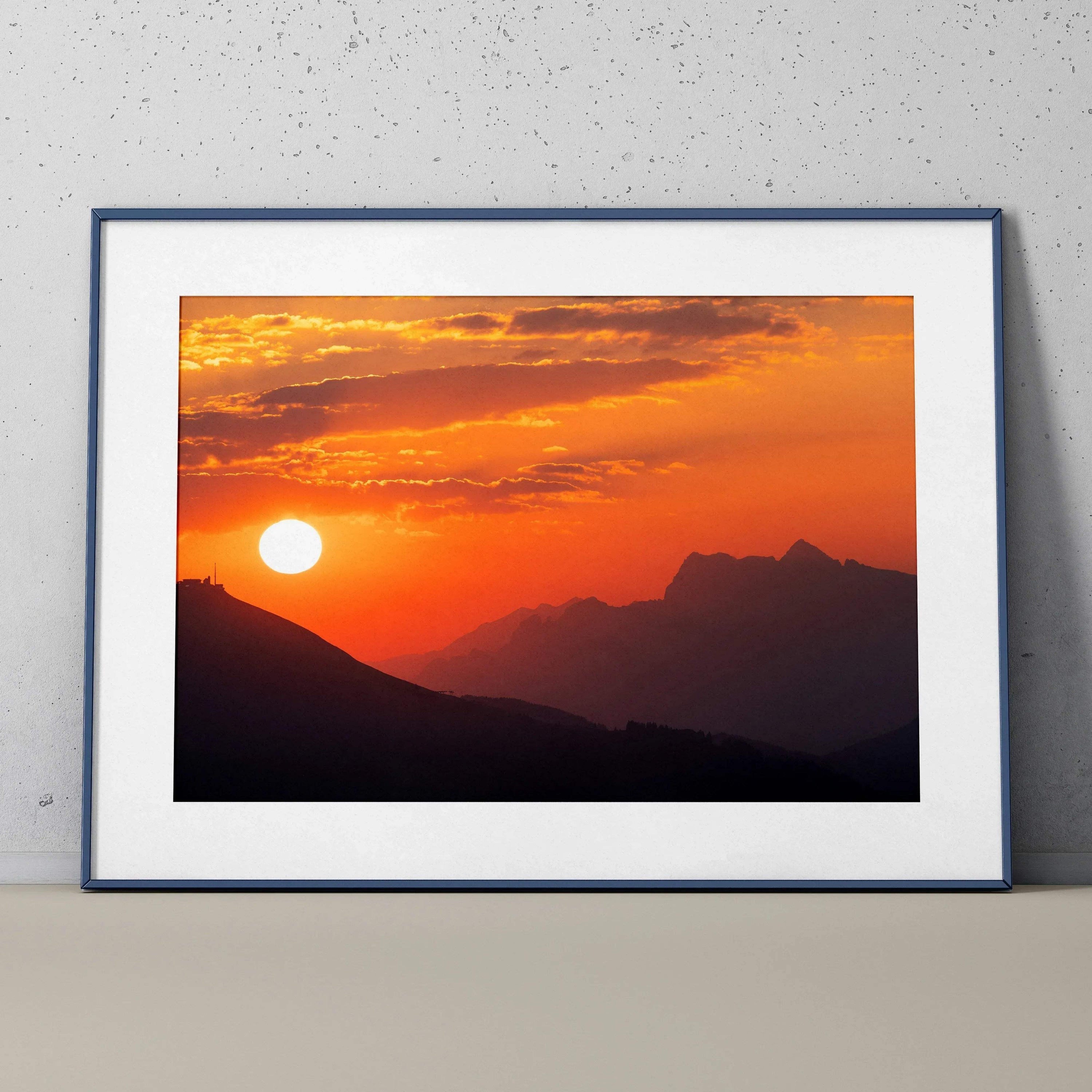 Framed mountain sunset poster with vibrant orange sky and silhouetted peaks, wall art print.