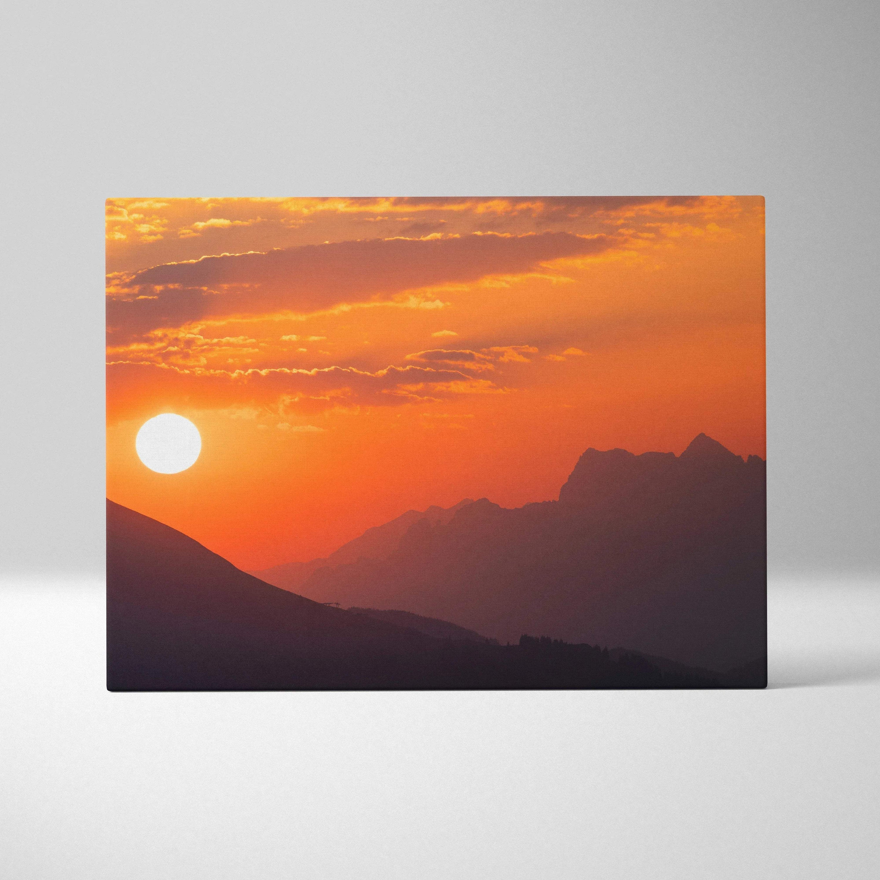 Canvas wall art featuring a vibrant orange mountain sunset with a glowing sun and layered peaks.
