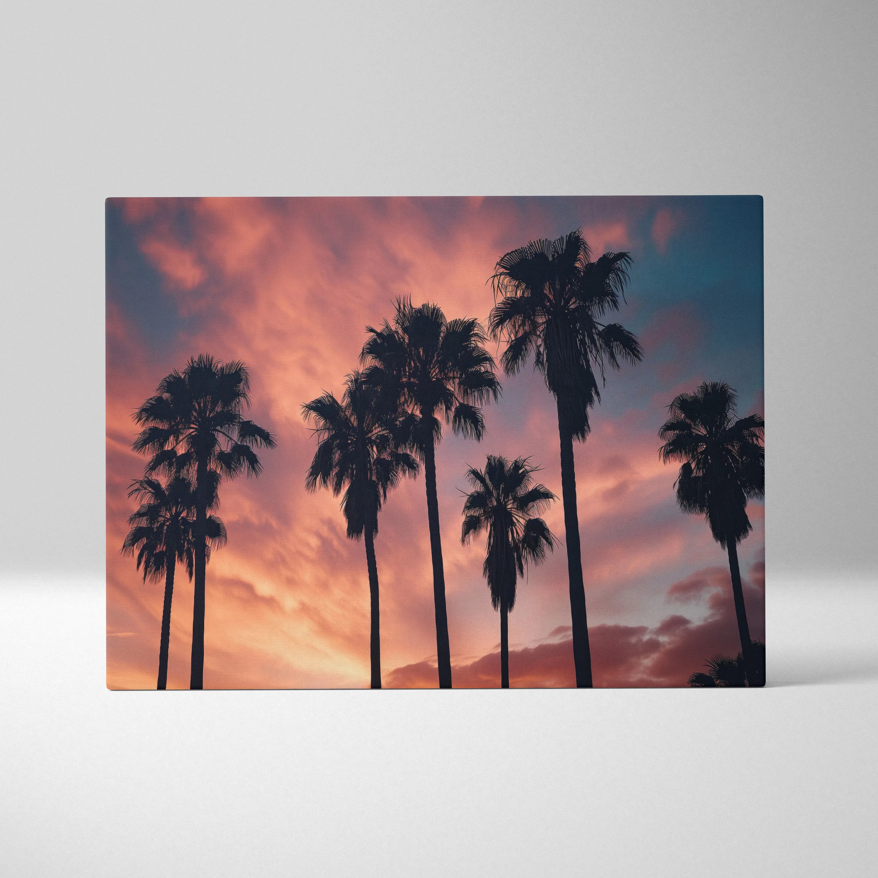 Canvas art featuring black palm tree silhouettes against a vibrant orange and purple sunset sky.