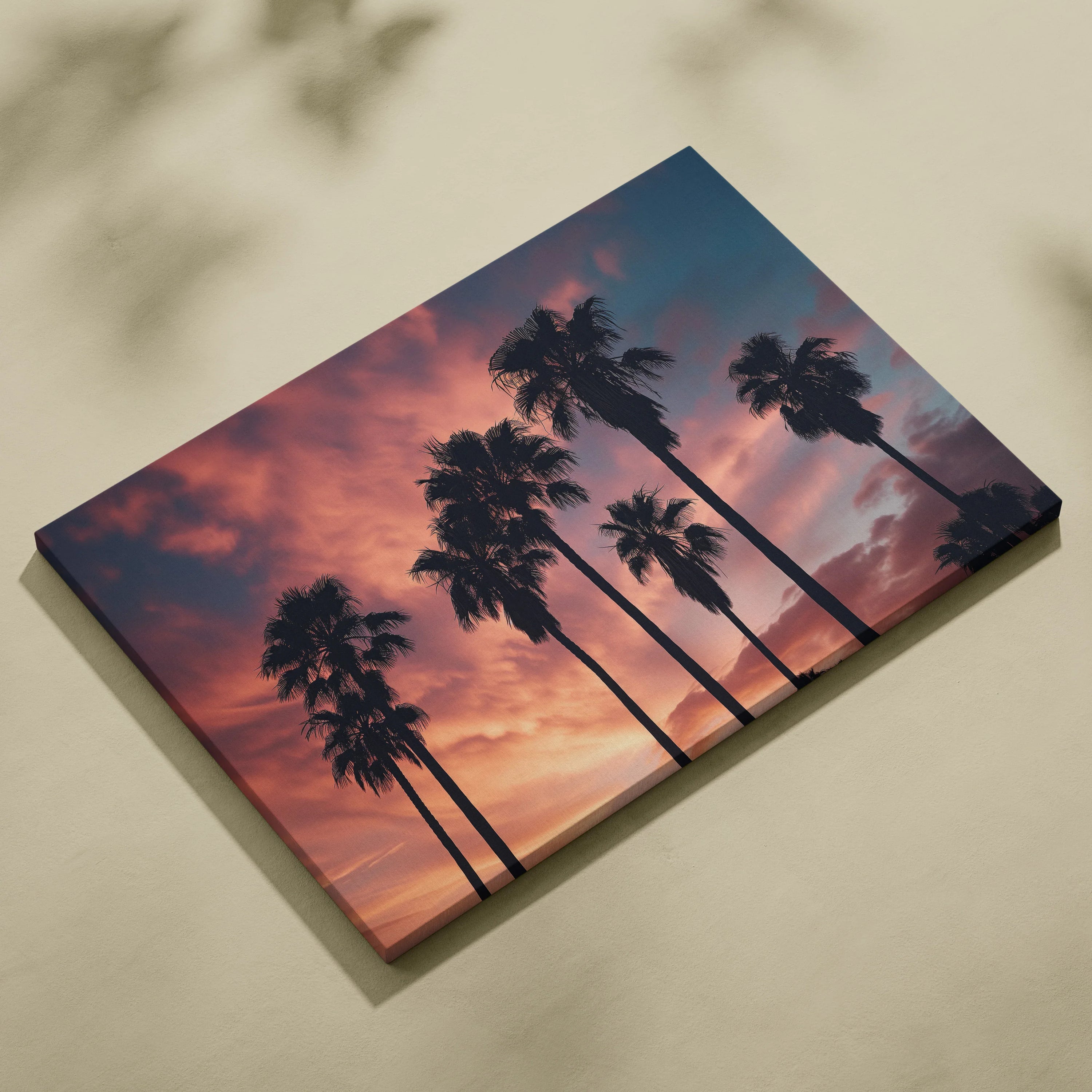 Canvas art featuring a tropical sunset with black palm tree silhouettes against a vibrant orange and purple sky.