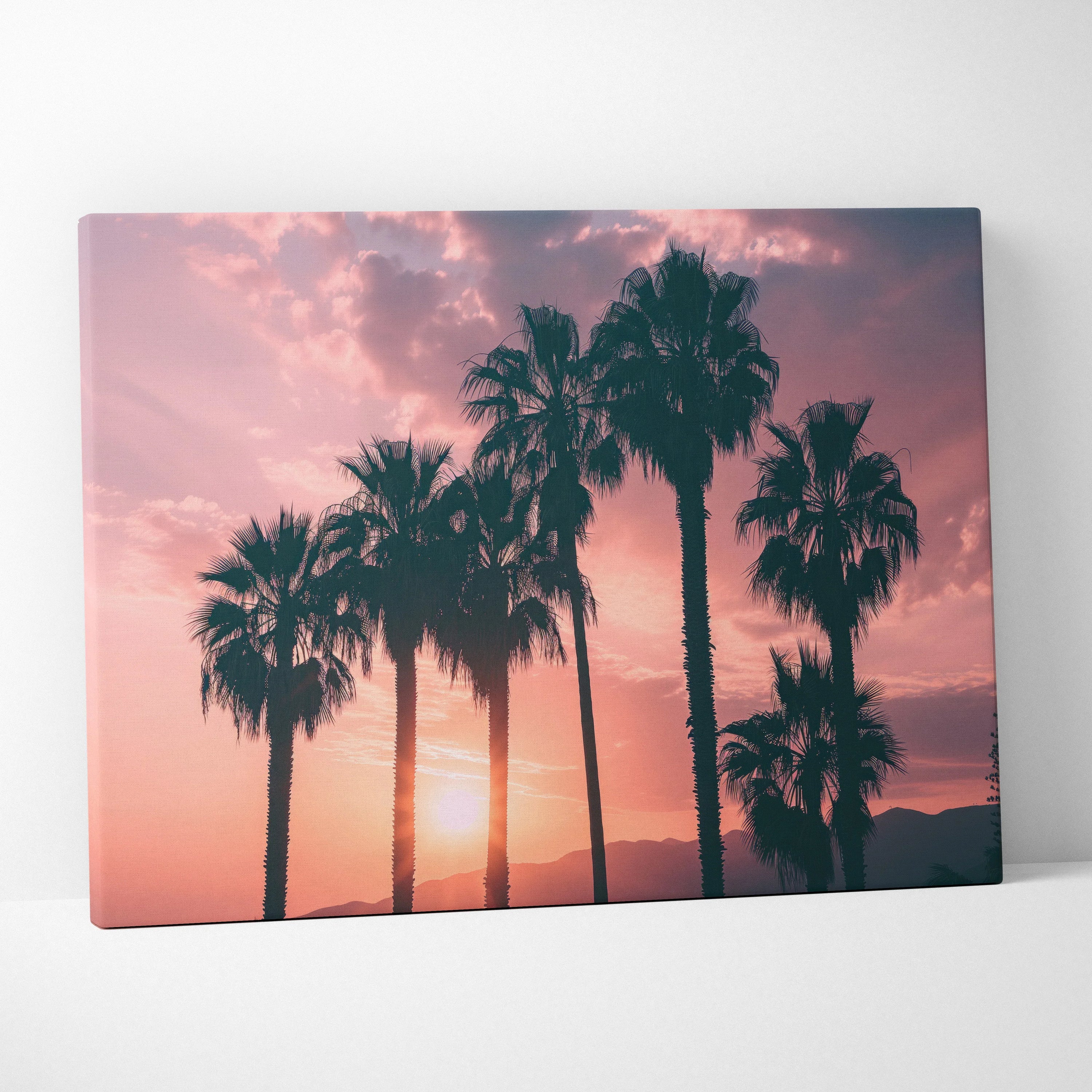 Canvas wall art featuring black palm tree silhouettes against a warm pink and orange sunset sky.