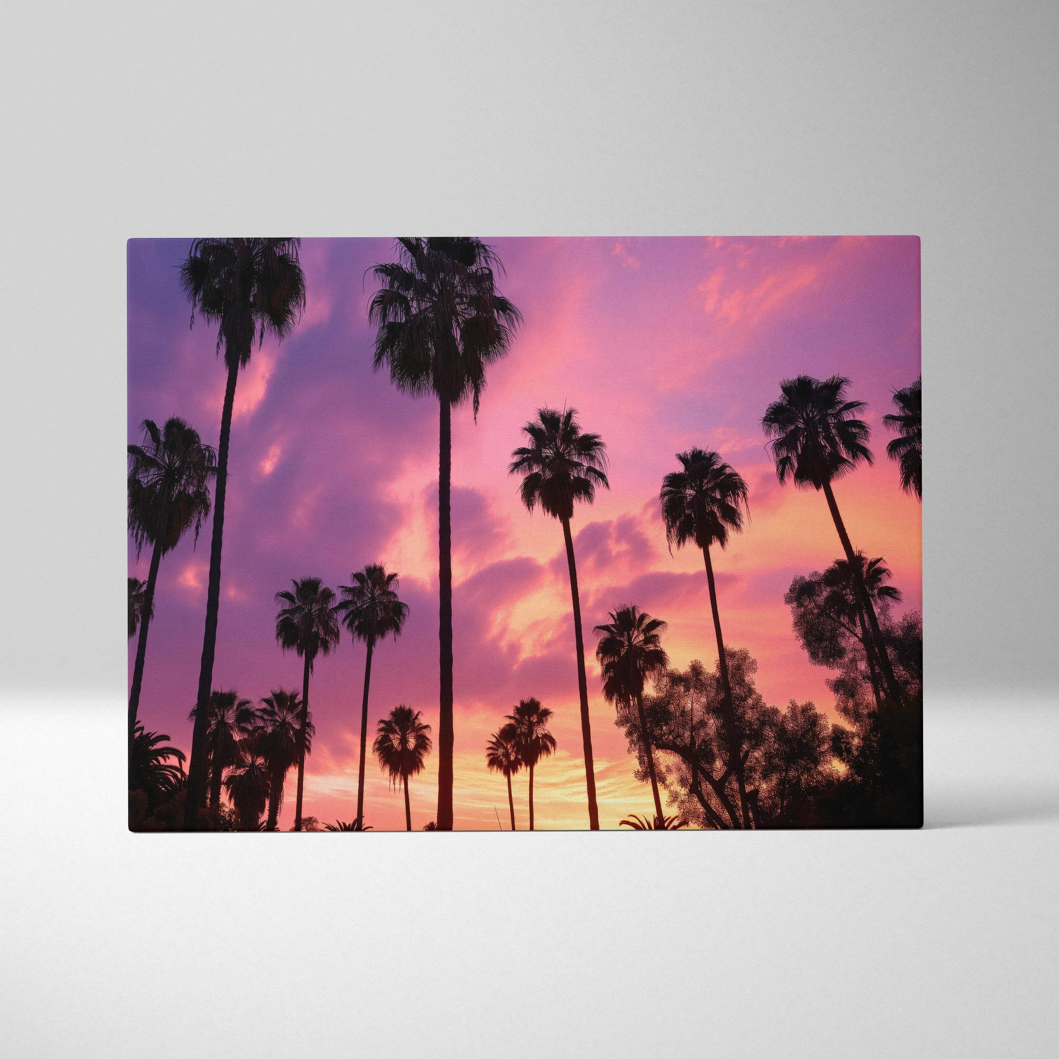 A rectangular canvas wall art of silhouetted palm trees against a vibrant purple to coral sunset sky with warm glow