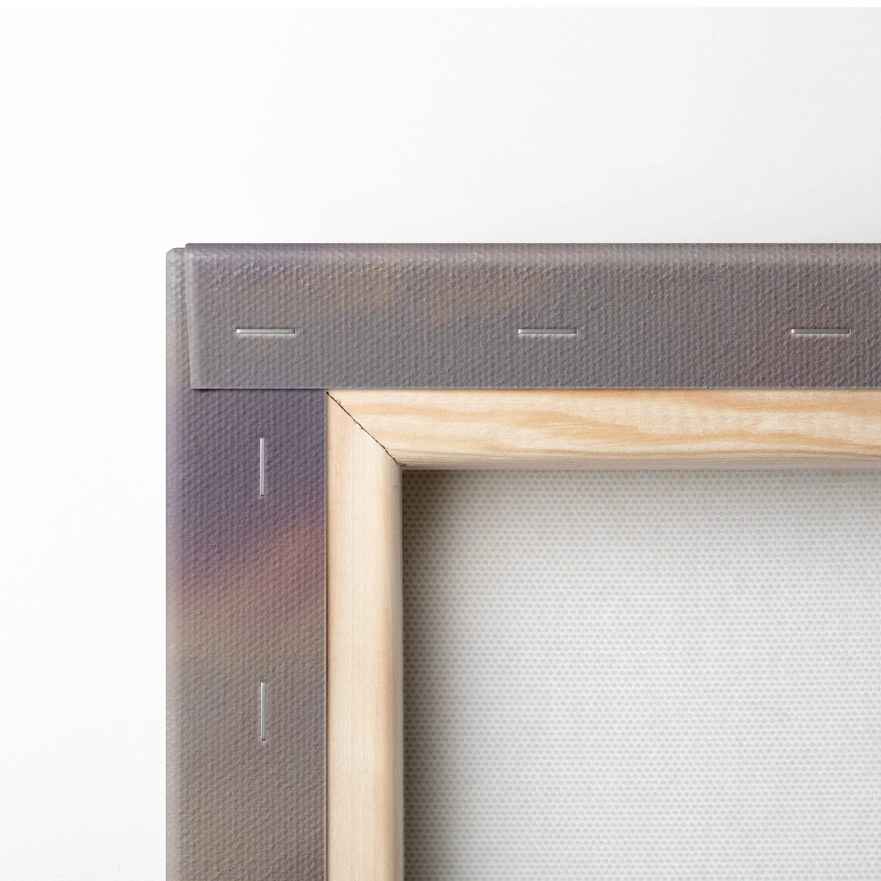 Close-up of natural wood frame corner with white stretched canvas and stapled edges for wall art.