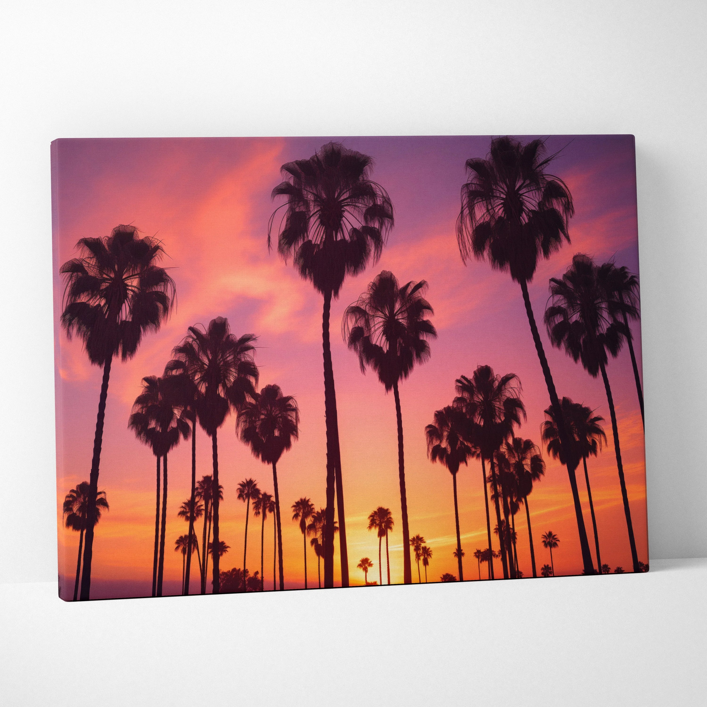Canvas wall art featuring black palm tree silhouettes against a vibrant orange and pink tropical sunset sky.