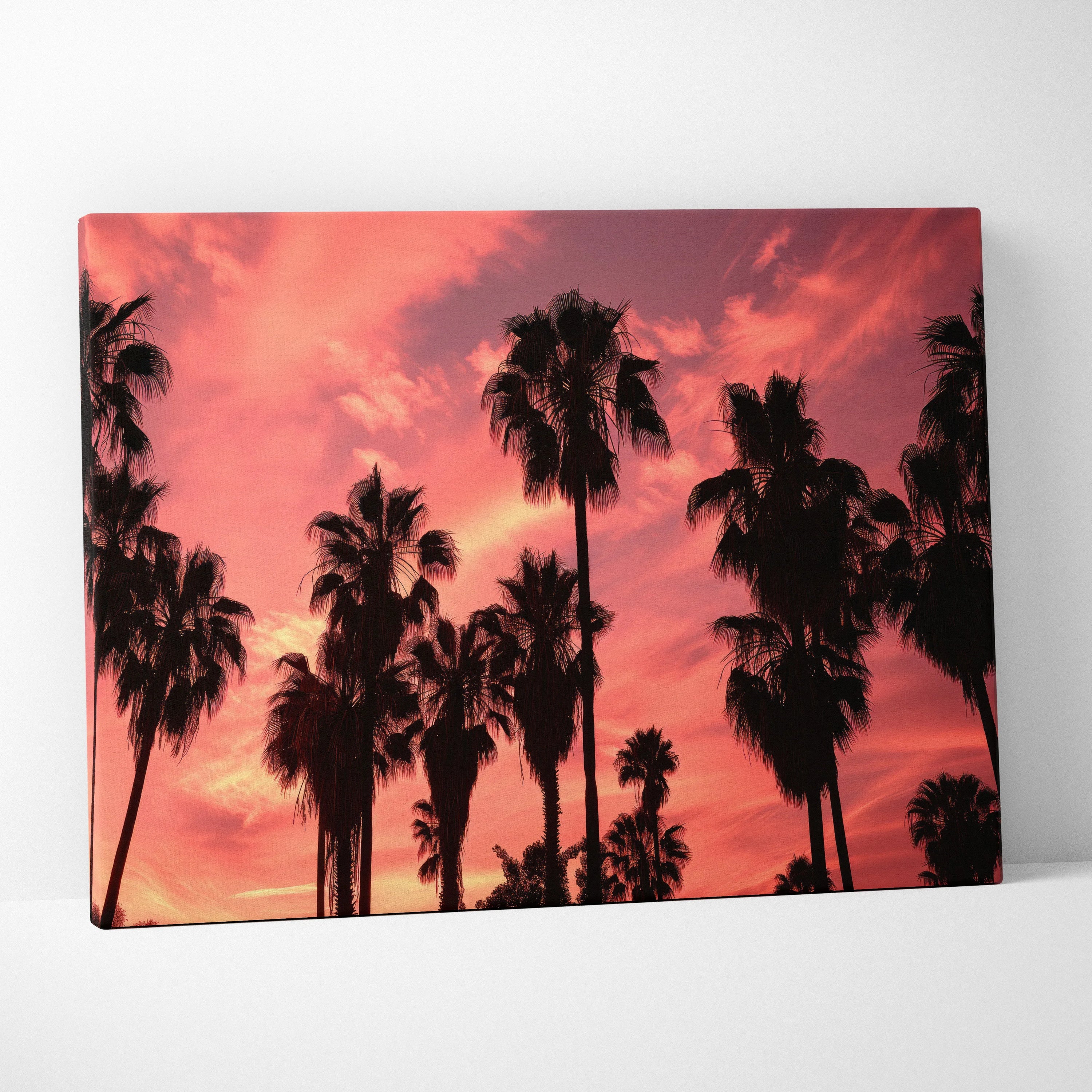 Canvas art featuring black palm tree silhouettes against a vivid pink and orange sunset sky.