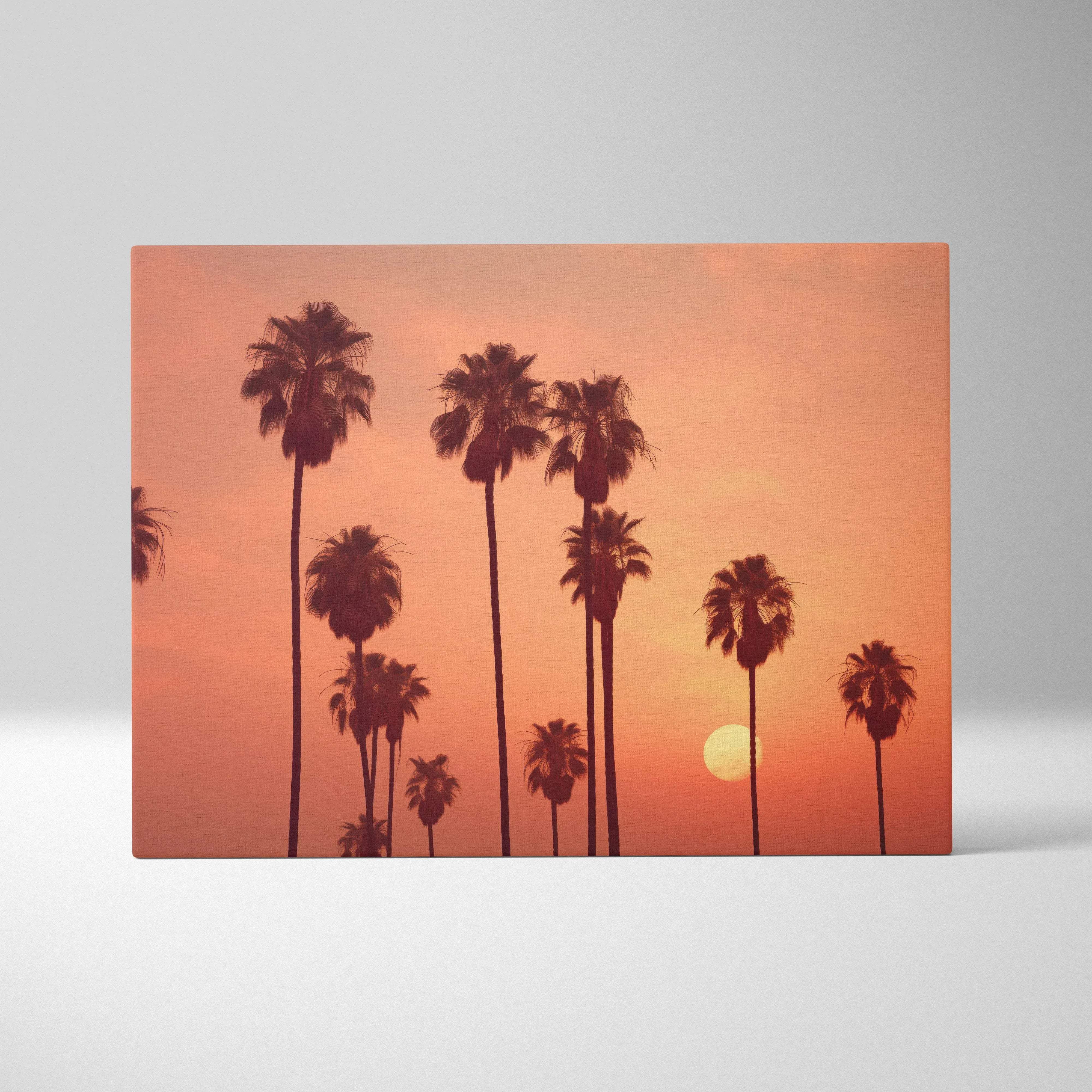 Rectangular canvas wall art featuring silhouetted palm trees against a warm orange sunset sky with the sun near horizon