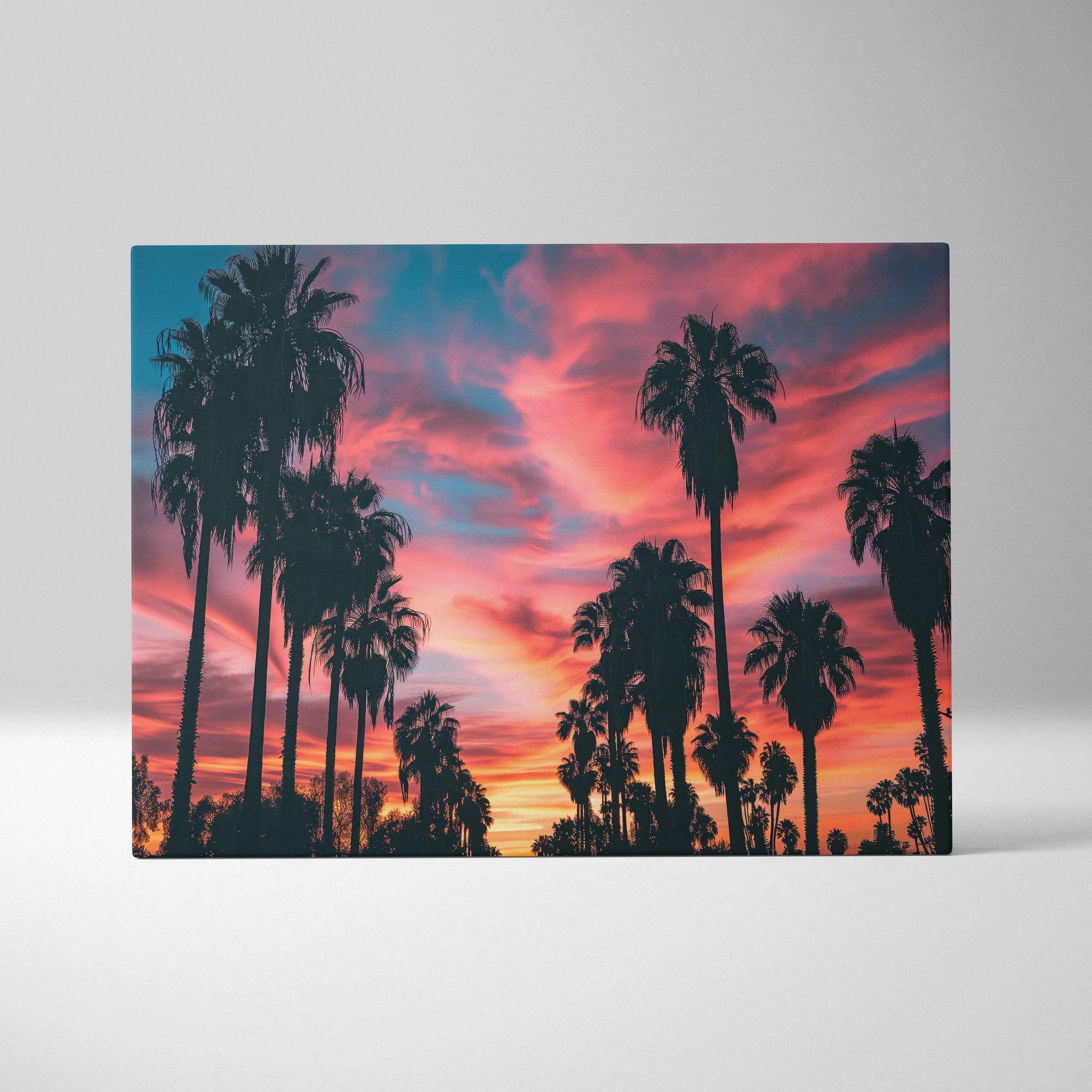 A rectangular canvas wall art featuring silhouetted palm trees against a warm orange pink sunset sky for living room decor