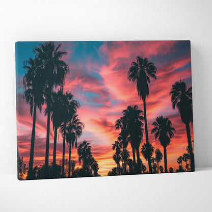 Canvas art featuring tall black palm tree silhouettes against a vivid tropical sunset sky in warm orange, pink, and purple.
