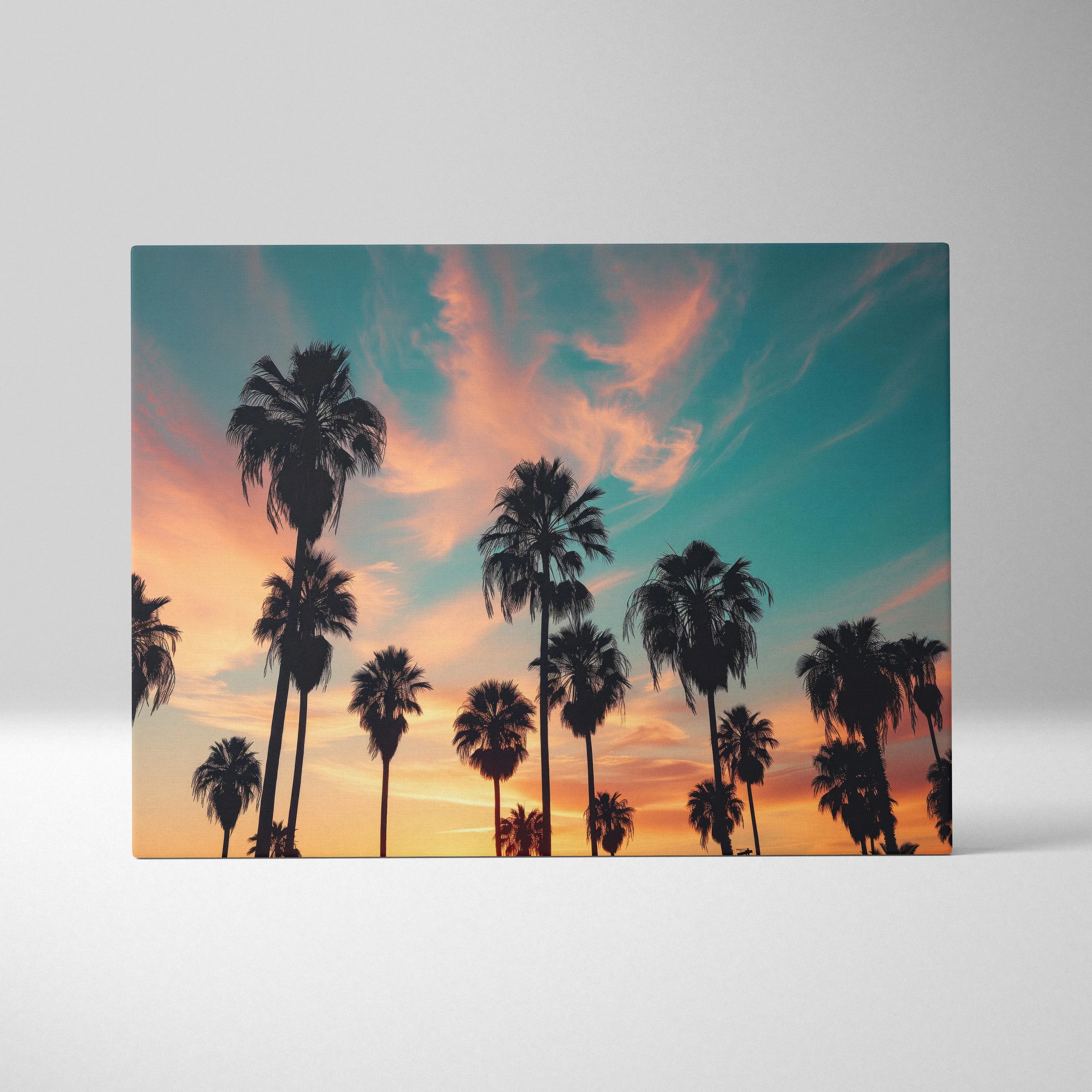 Canvas wall art featuring black silhouette palm trees against a vibrant orange and blue sunset sky.
