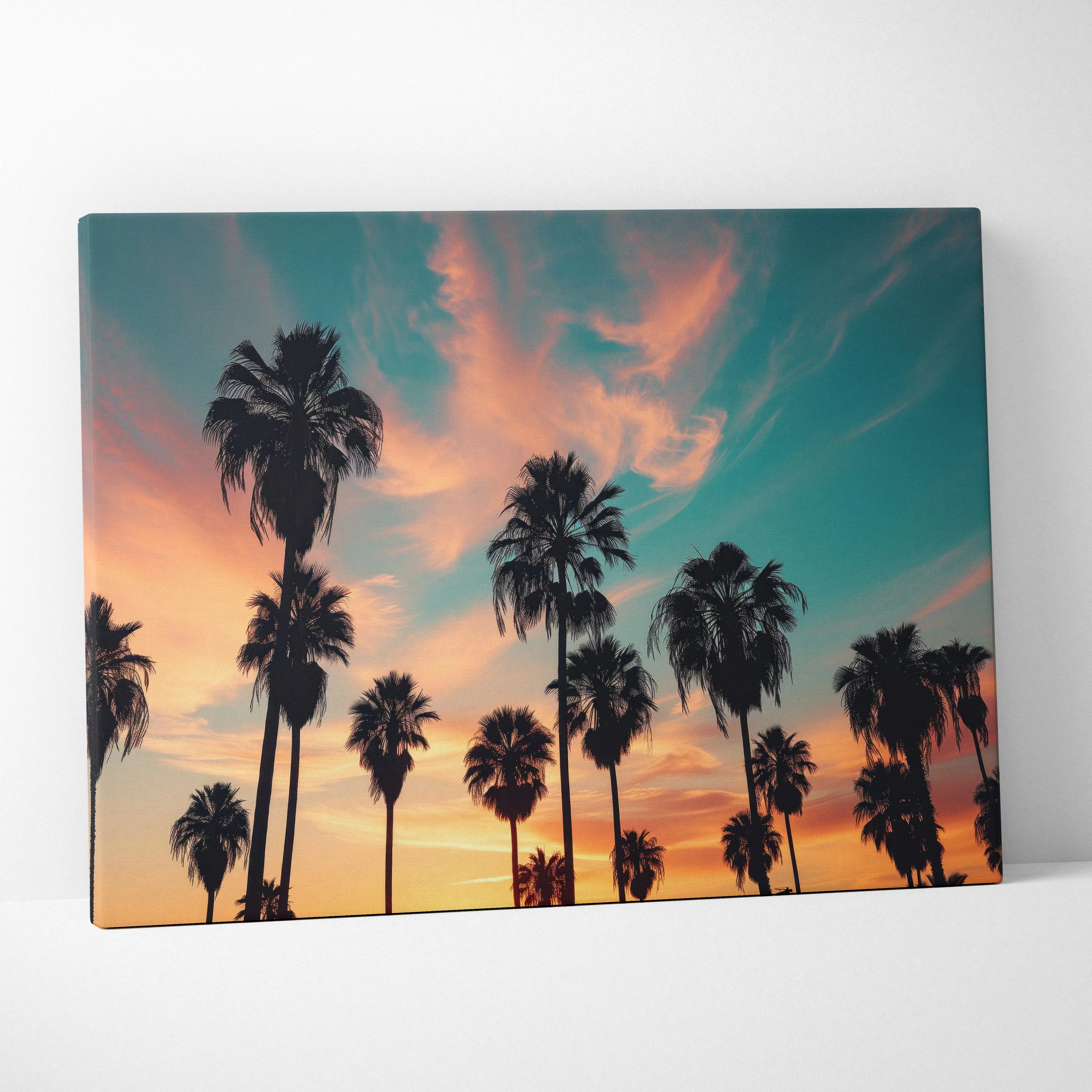 Canvas wall art featuring black silhouette palm trees against a vibrant sunset sky with orange and blue hues, perfect decor.