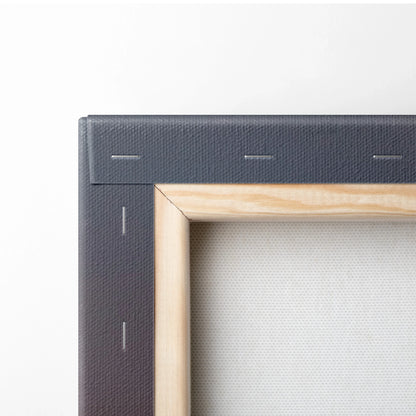 Close-up of stretched canvas corner with natural wood frame and staples securing black canvas backing.