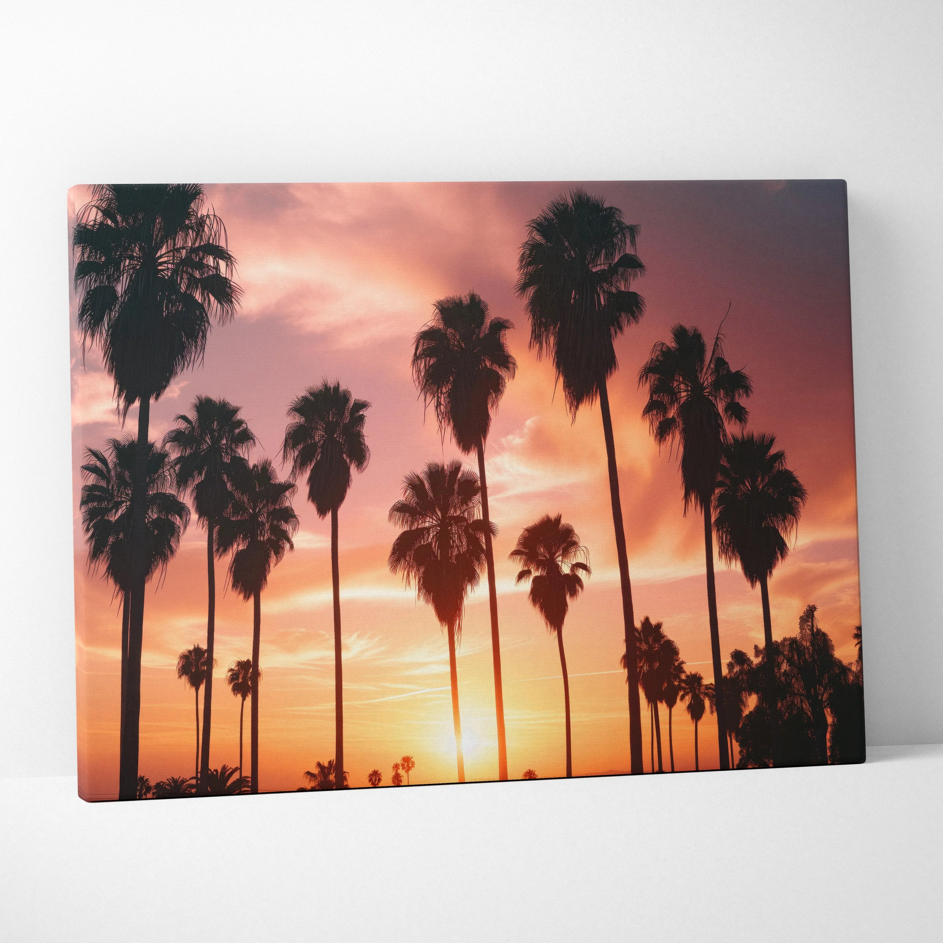 Canvas wall art featuring silhouetted palm trees against a vibrant orange and pink tropical sunset sky.