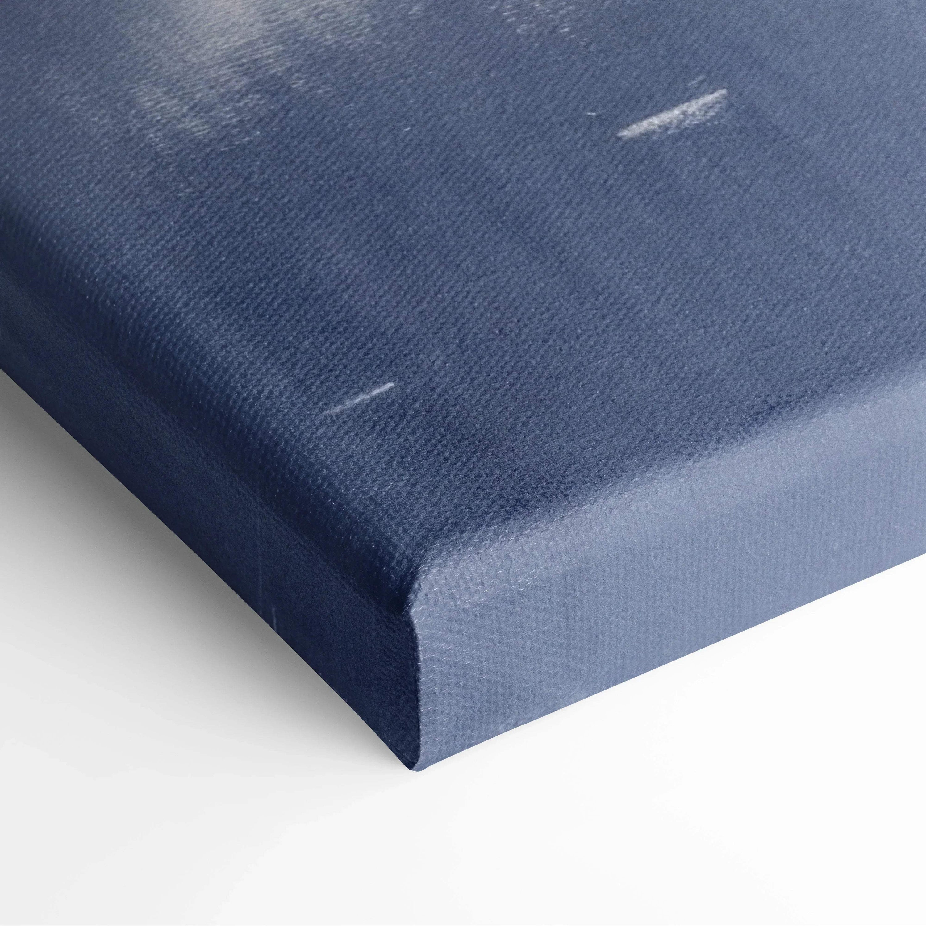 Close-up of a stretched canvas with deep blue and white snowy landscape print corner for wall art decor.