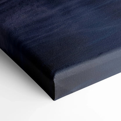 Close-up of stretched canvas edge with dark blue and black winter sunset tones on textured fabric wall art.
